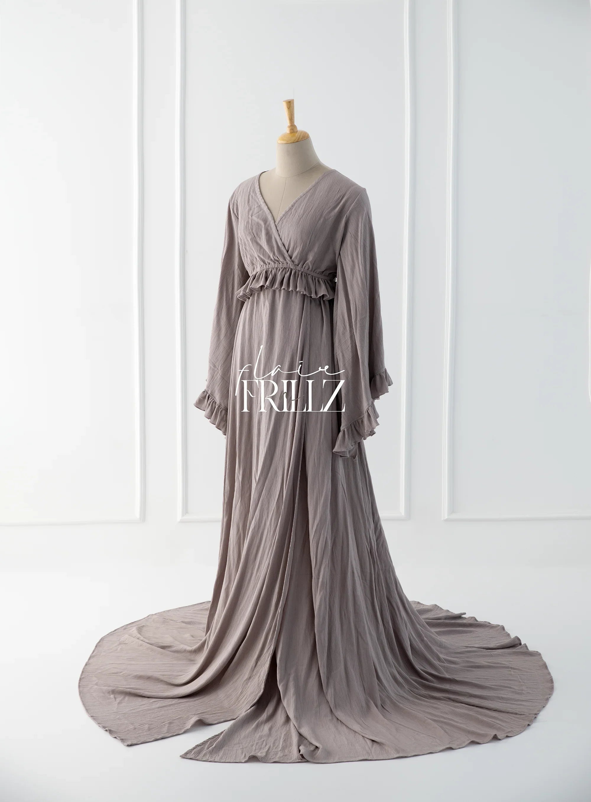 Taupe boho maternity gown with ruffled waist detail and long flowing sleeves on mannequin