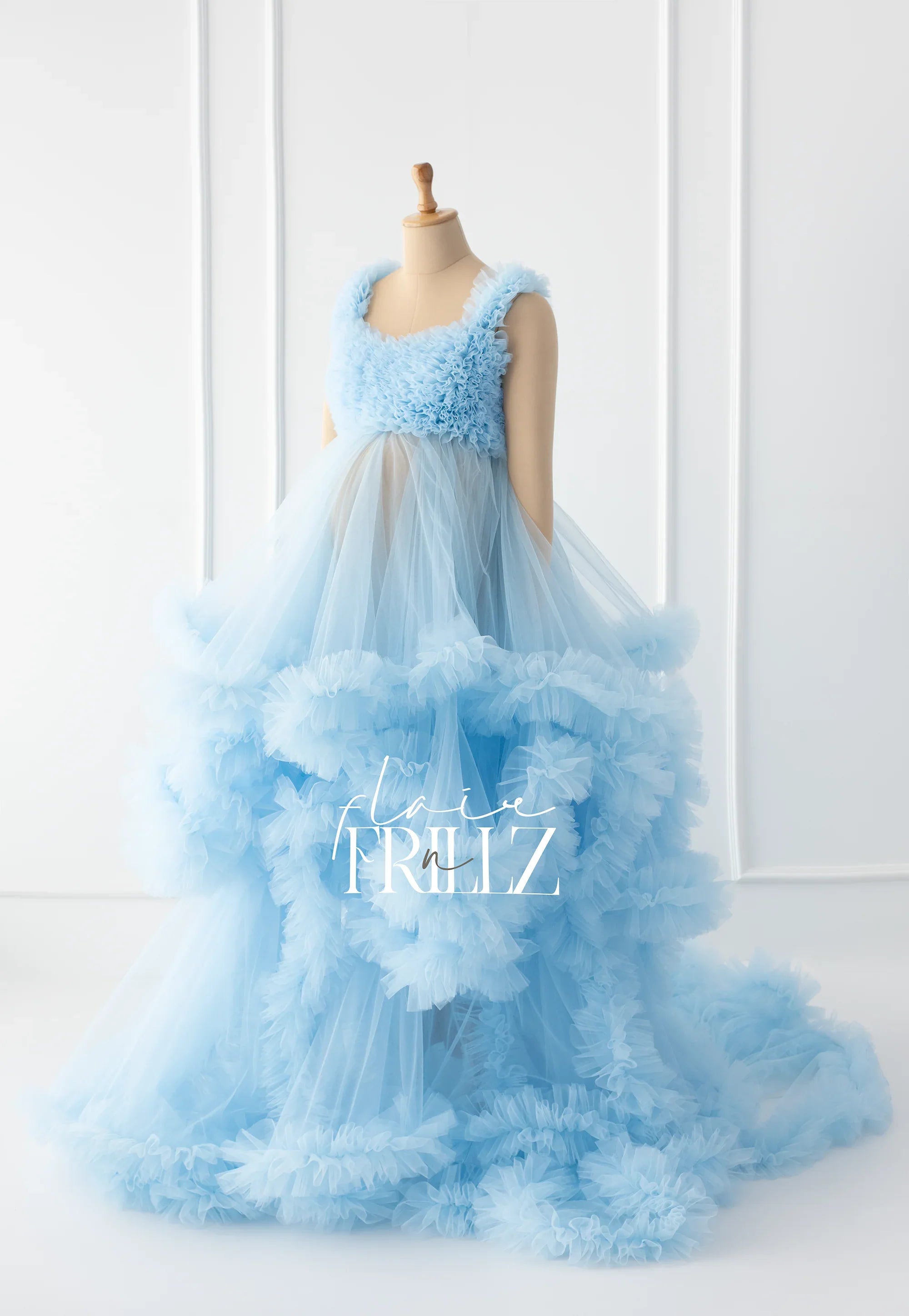 Light blue ruffled tulle maternity gown on mannequin in bright minimal studio