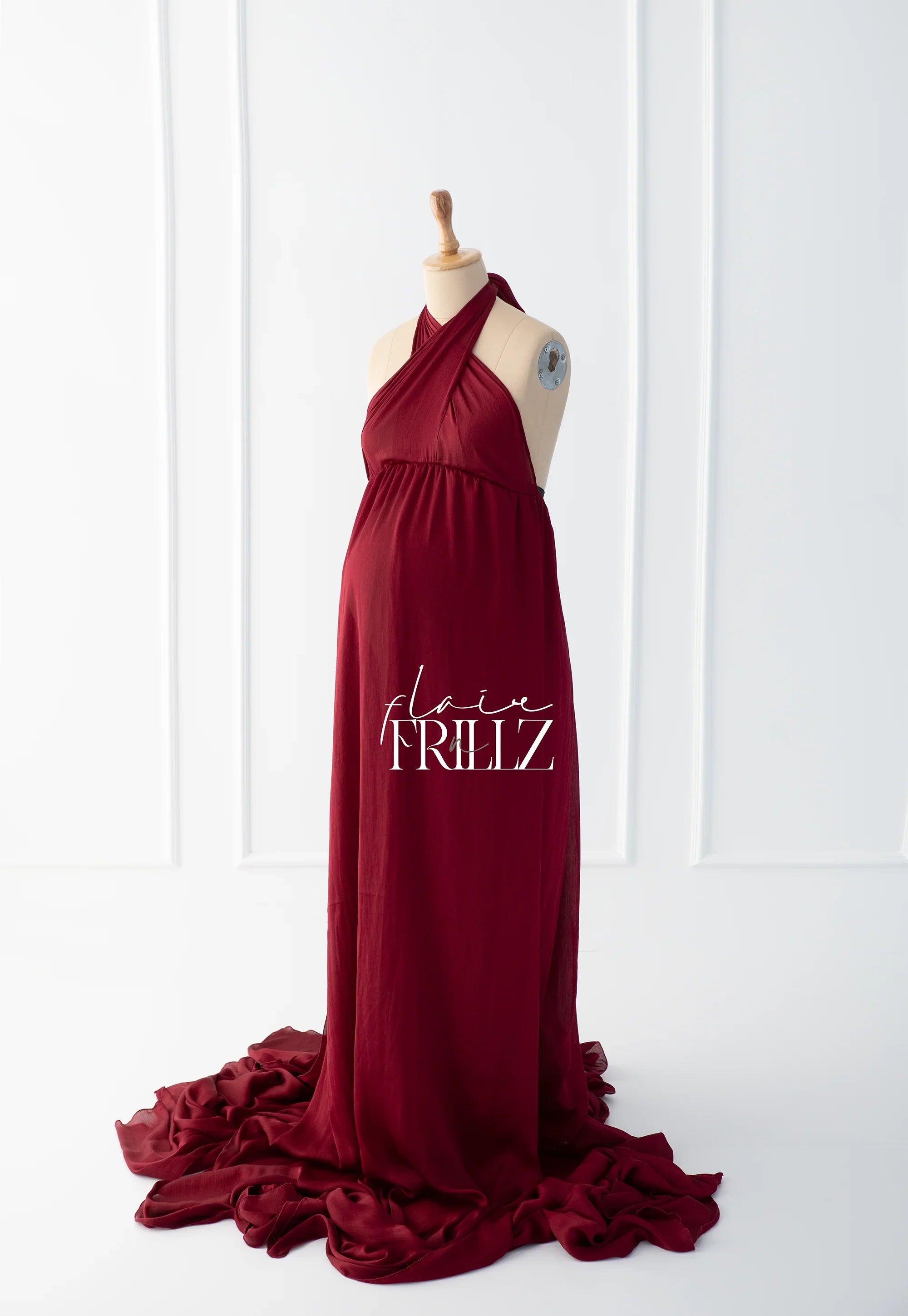 Elegant burgundy maternity gown with halter neck and flowing train on mannequin