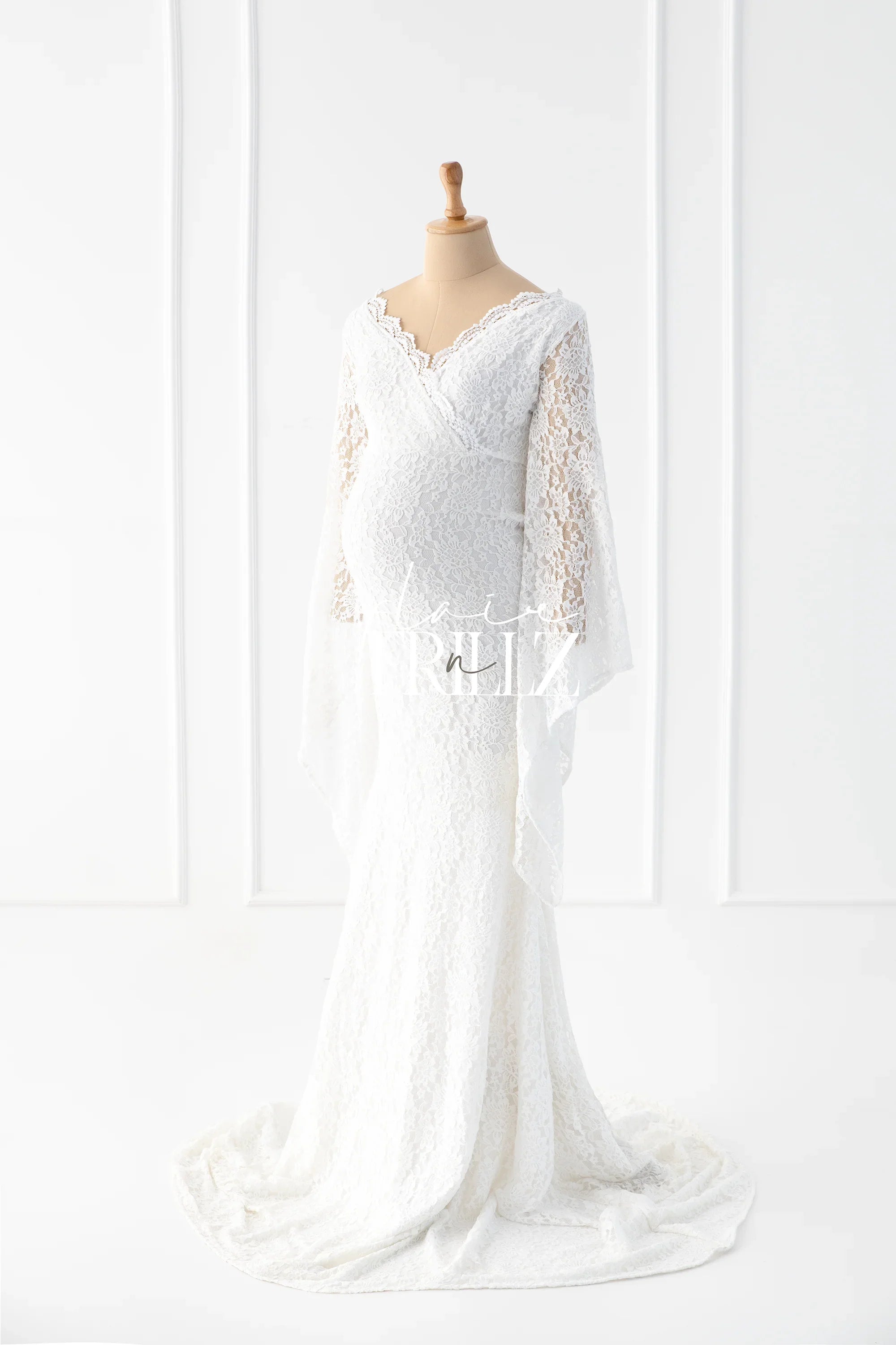 White lace maternity gown with long sleeves and V-neck on a dress form