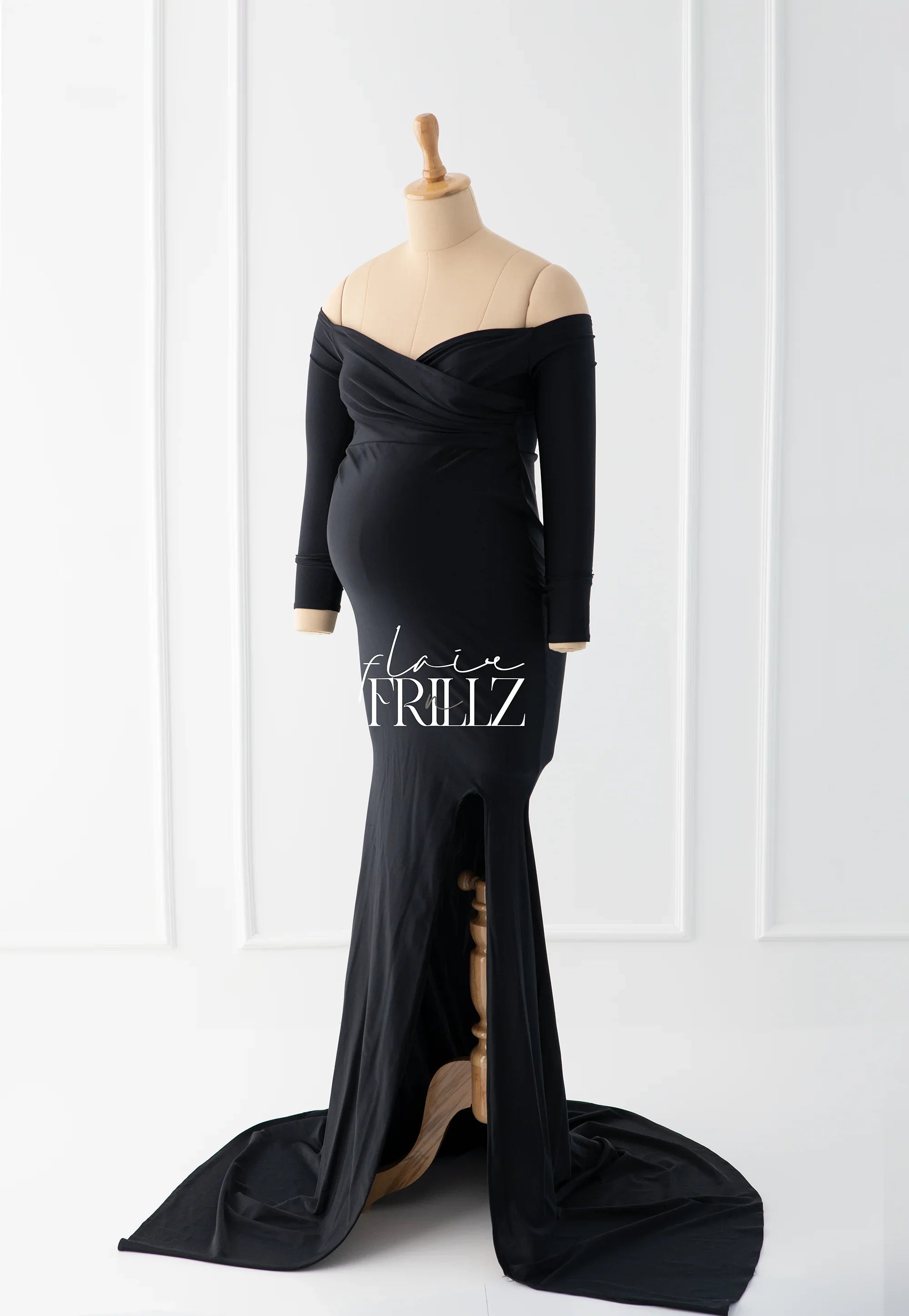 Elegant black off-shoulder maternity gown with long sleeves on mannequin, floor-length train