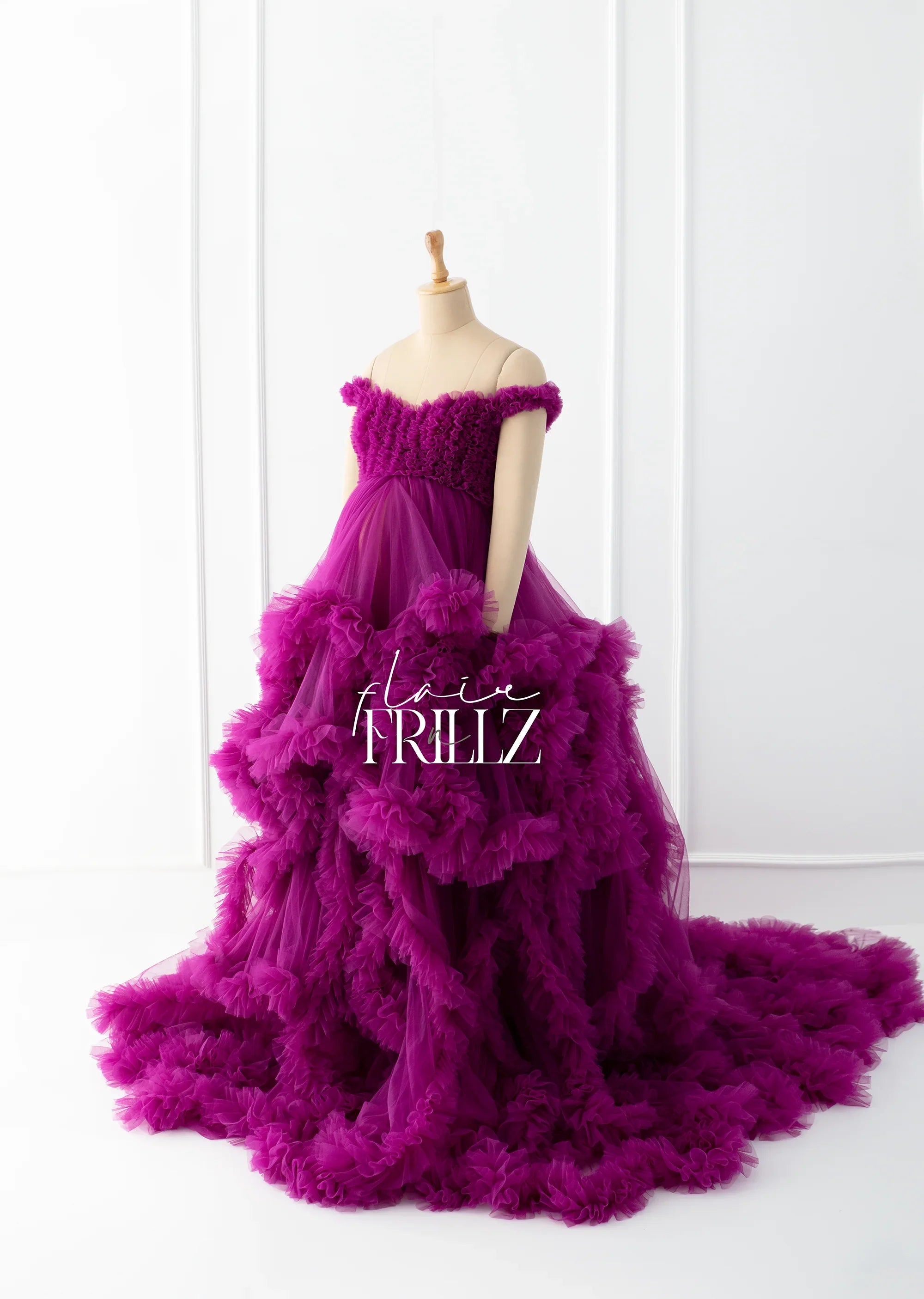 Elegant purple off-shoulder maternity gown with layered ruffles on mannequin