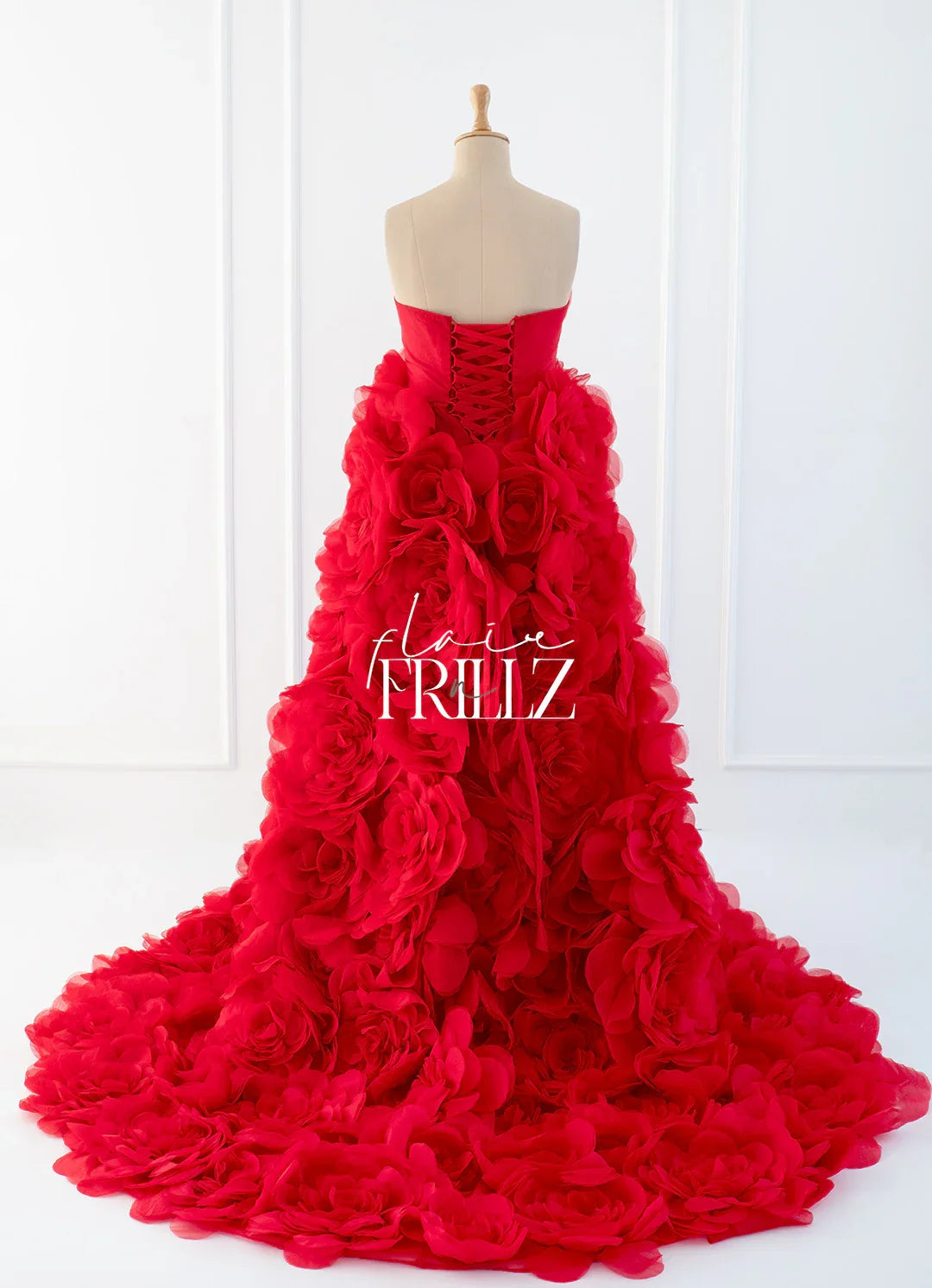 Red strapless maternity gown with floral ruffles and a long flowing train on a mannequin