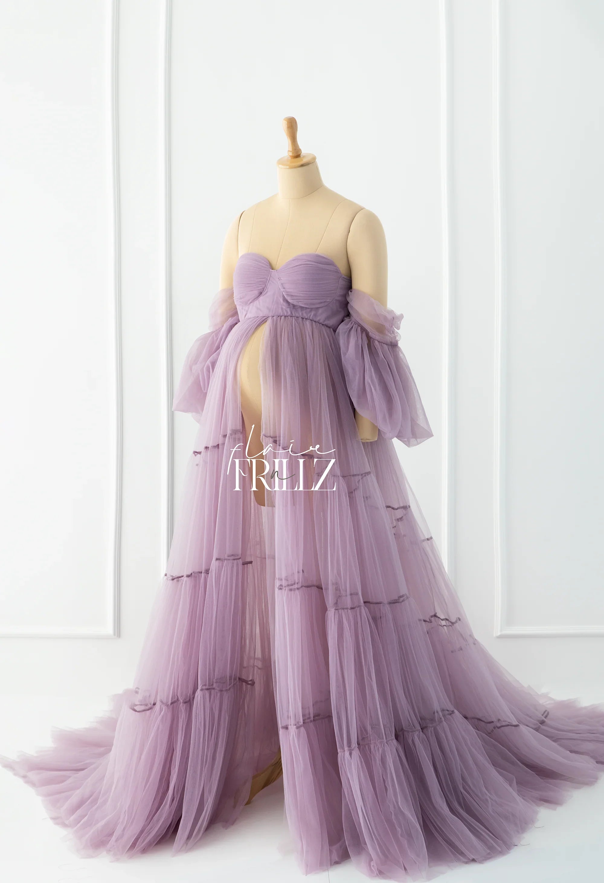 Lilac tulle maternity gown with off-shoulder sleeves and flowing layered skirt on mannequin