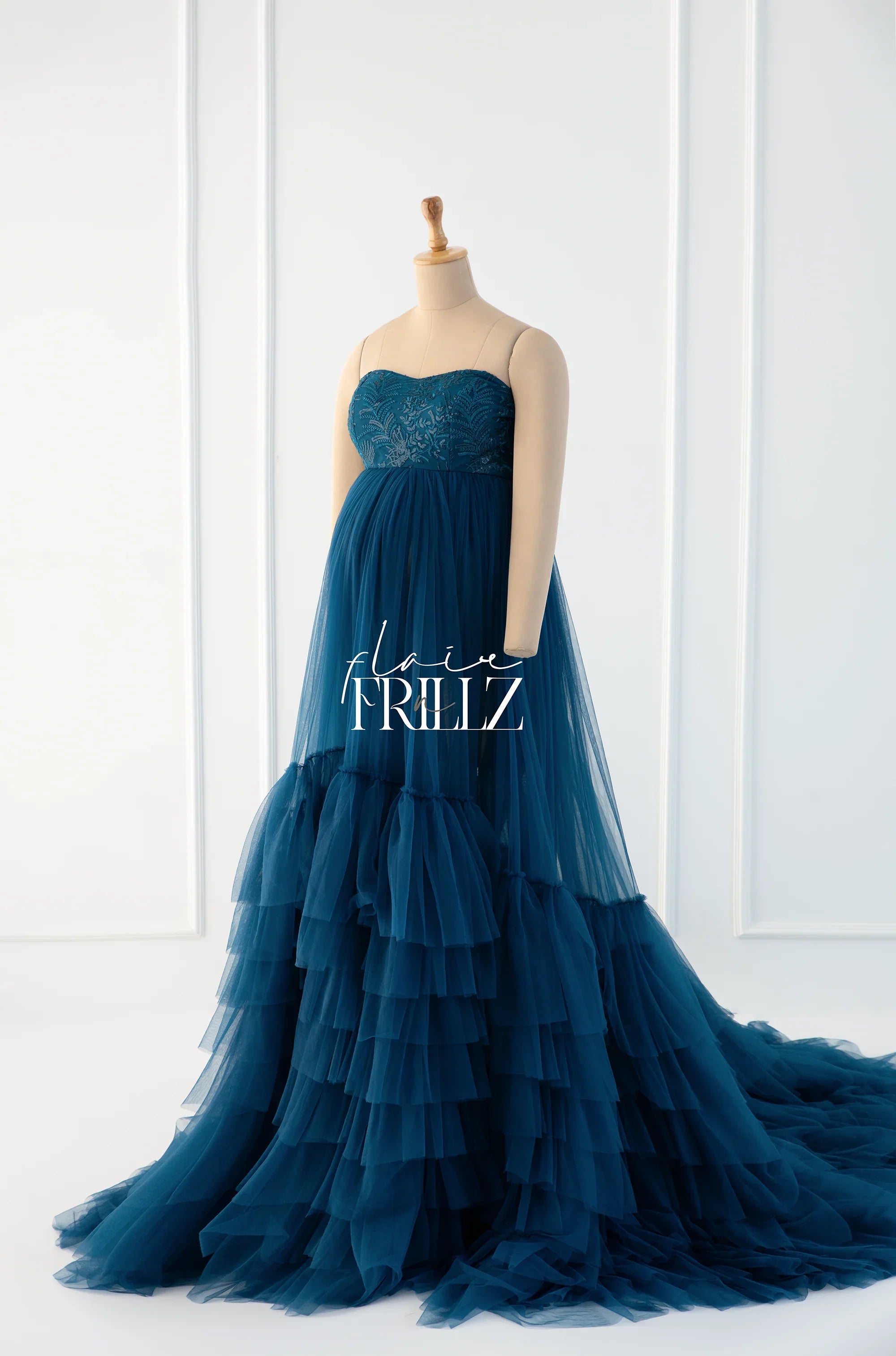Elegant teal maternity gown with lace bodice and tiered tulle skirt on mannequin