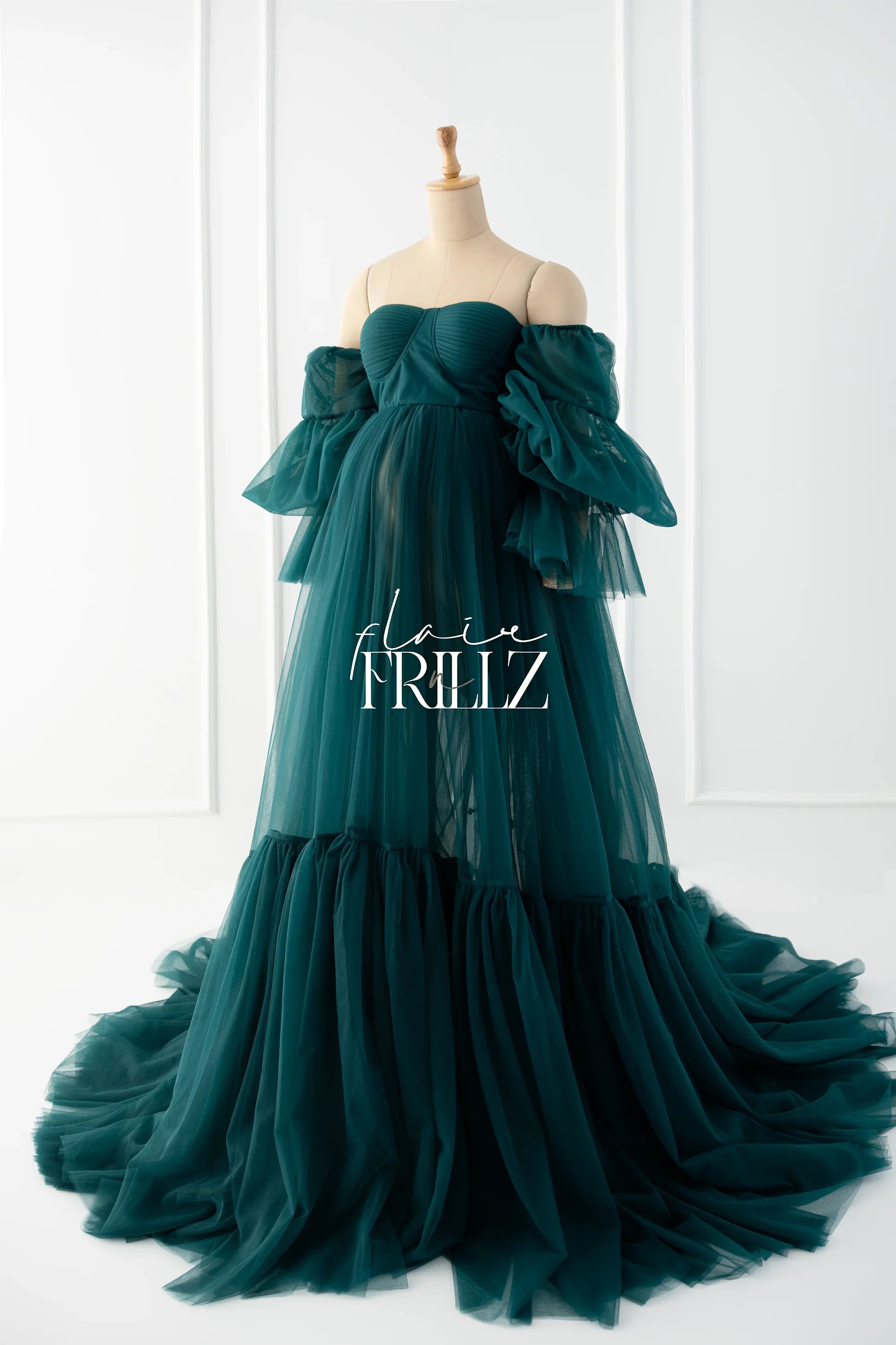 Emerald green off-shoulder maternity gown with ruffled tulle sleeves and flowing skirt on mannequin