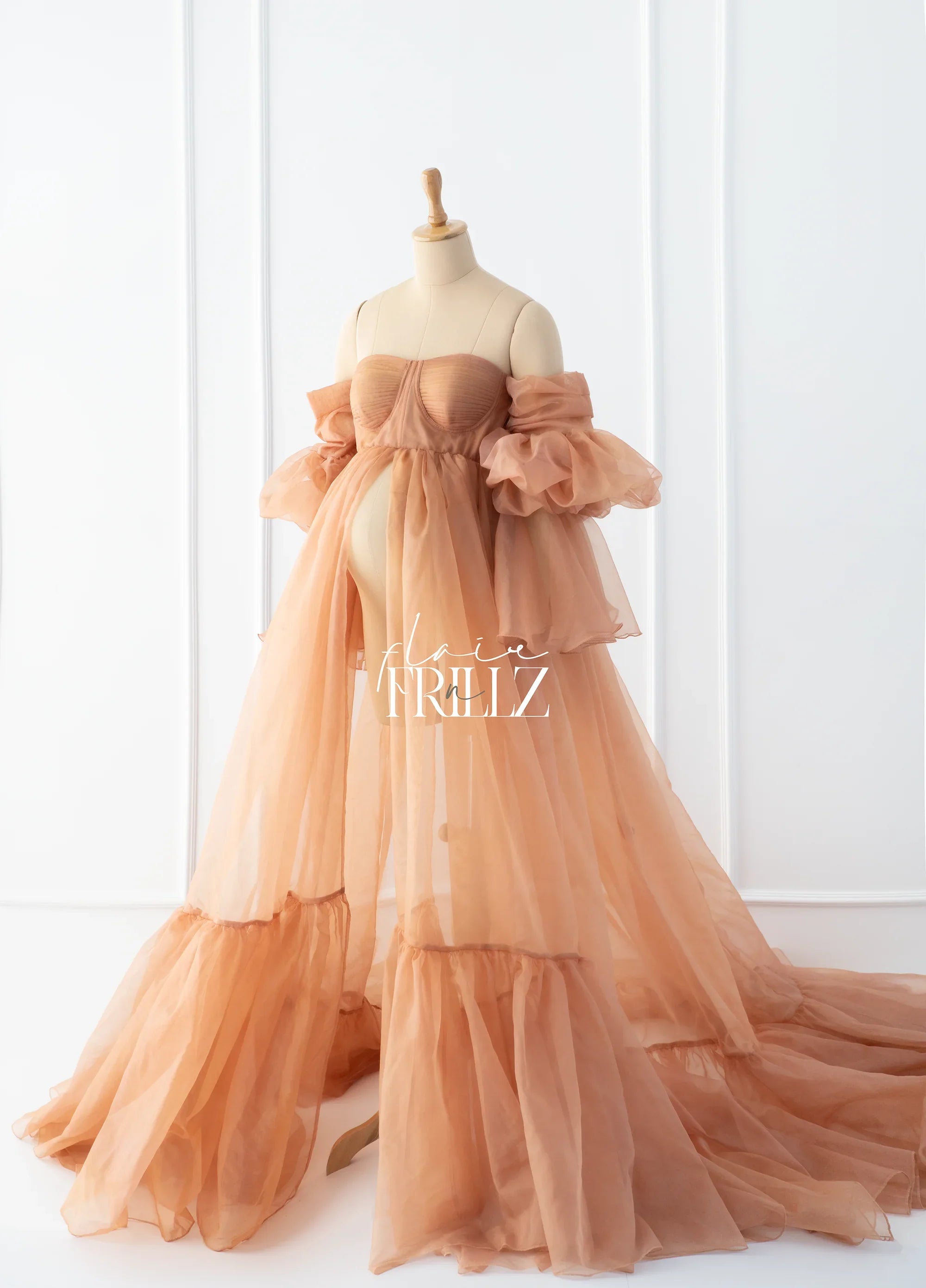 Peach sheer maternity gown with off-shoulder ruffled sleeves on mannequin