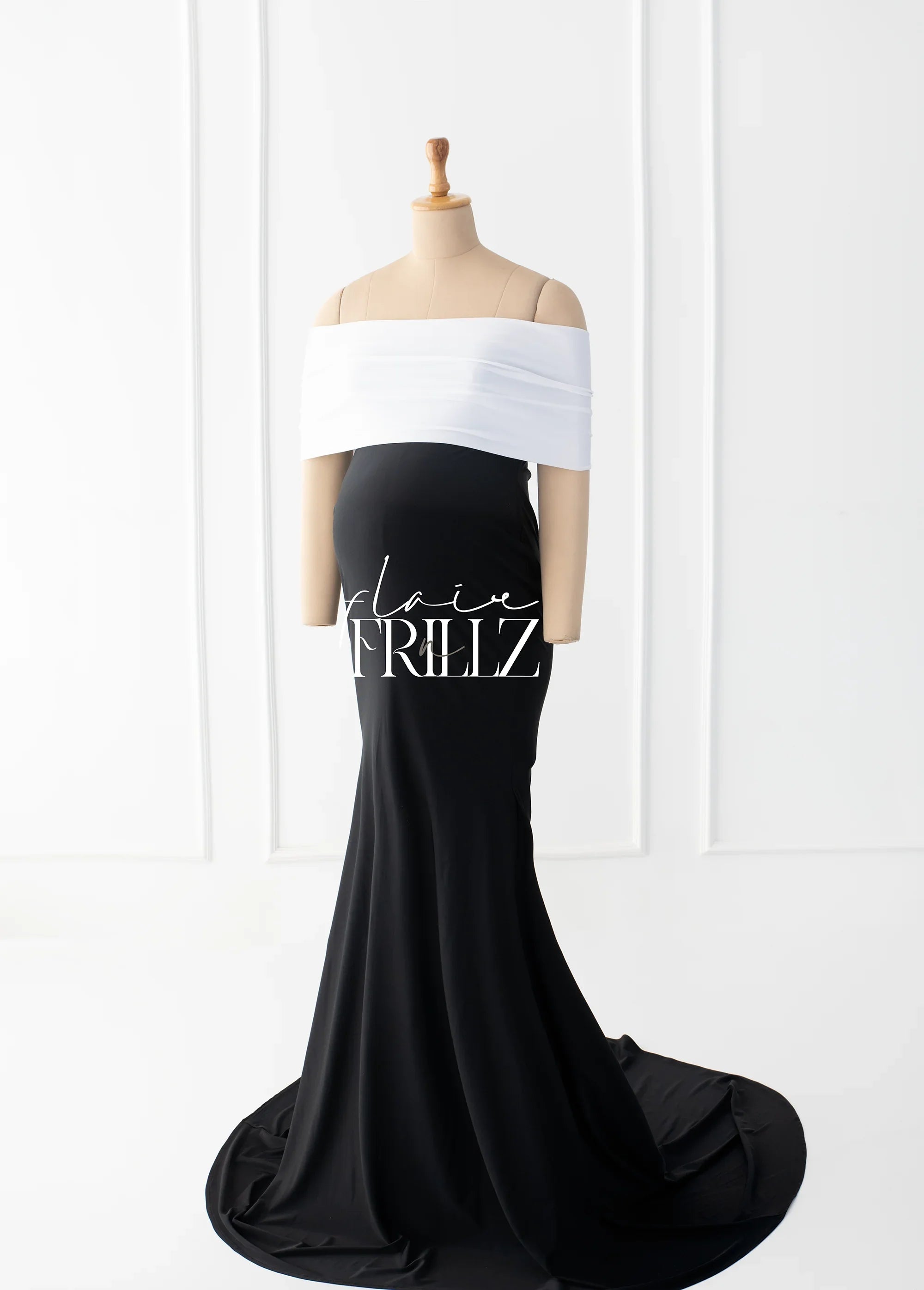 Elegant off-shoulder black and white maternity gown with fitted silhouette on mannequin