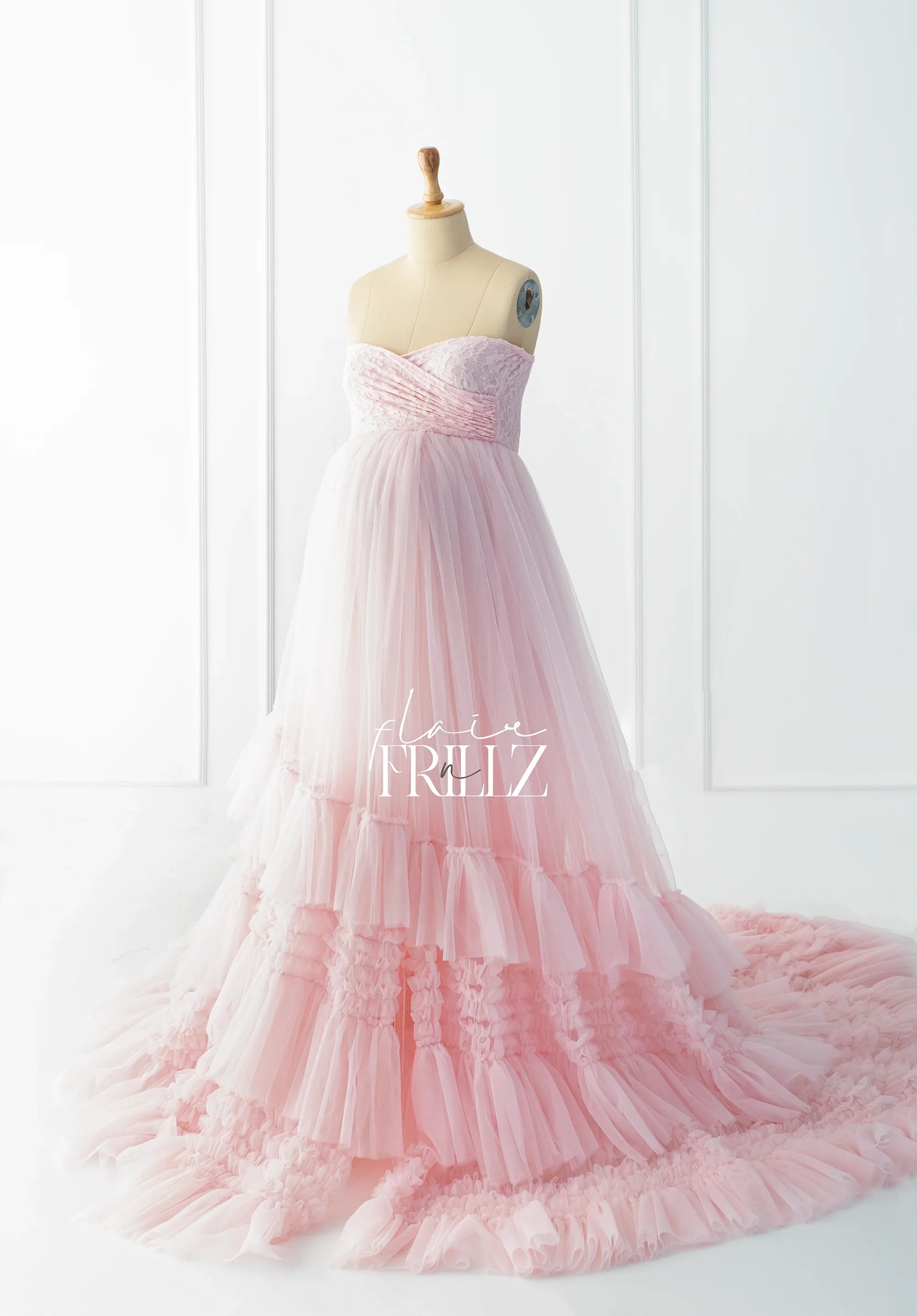 Light pink strapless maternity gown with lace bodice and tiered tulle skirt on mannequin