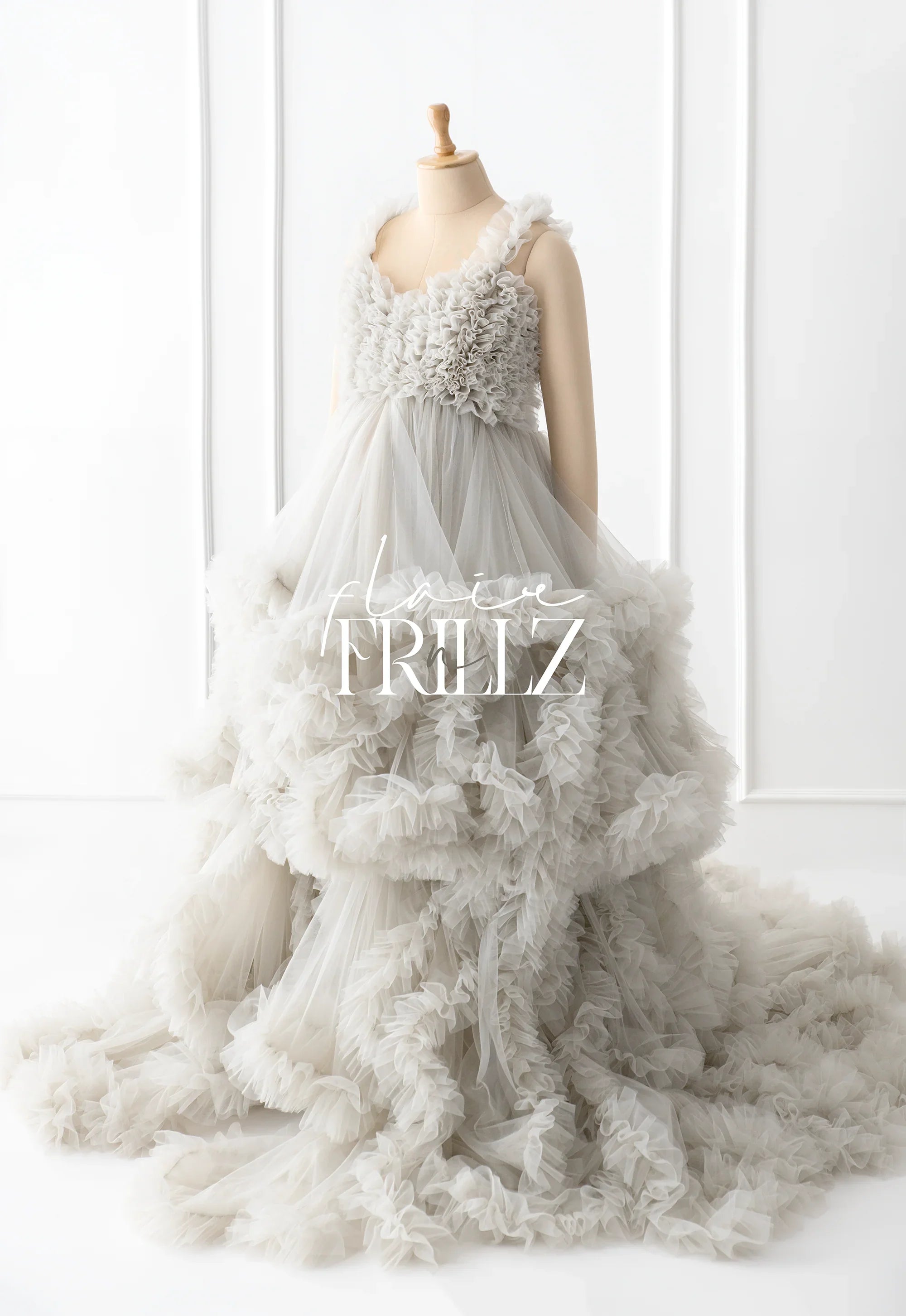 Elegant ruffled maternity gown with layered tulle skirt on mannequin in bright studio