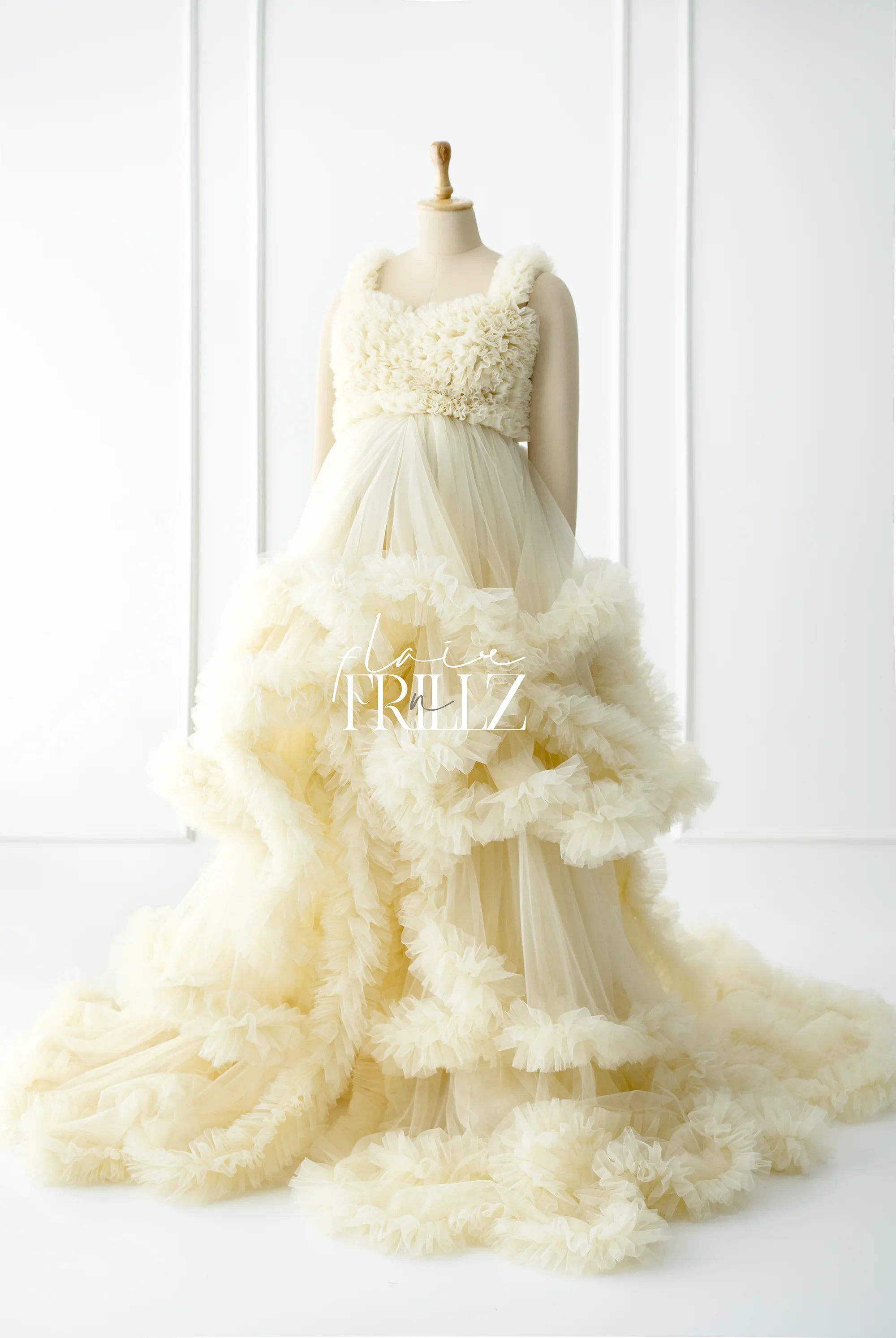 Ivory ruffled maternity gown with tulle layers displayed on mannequin in bright studio