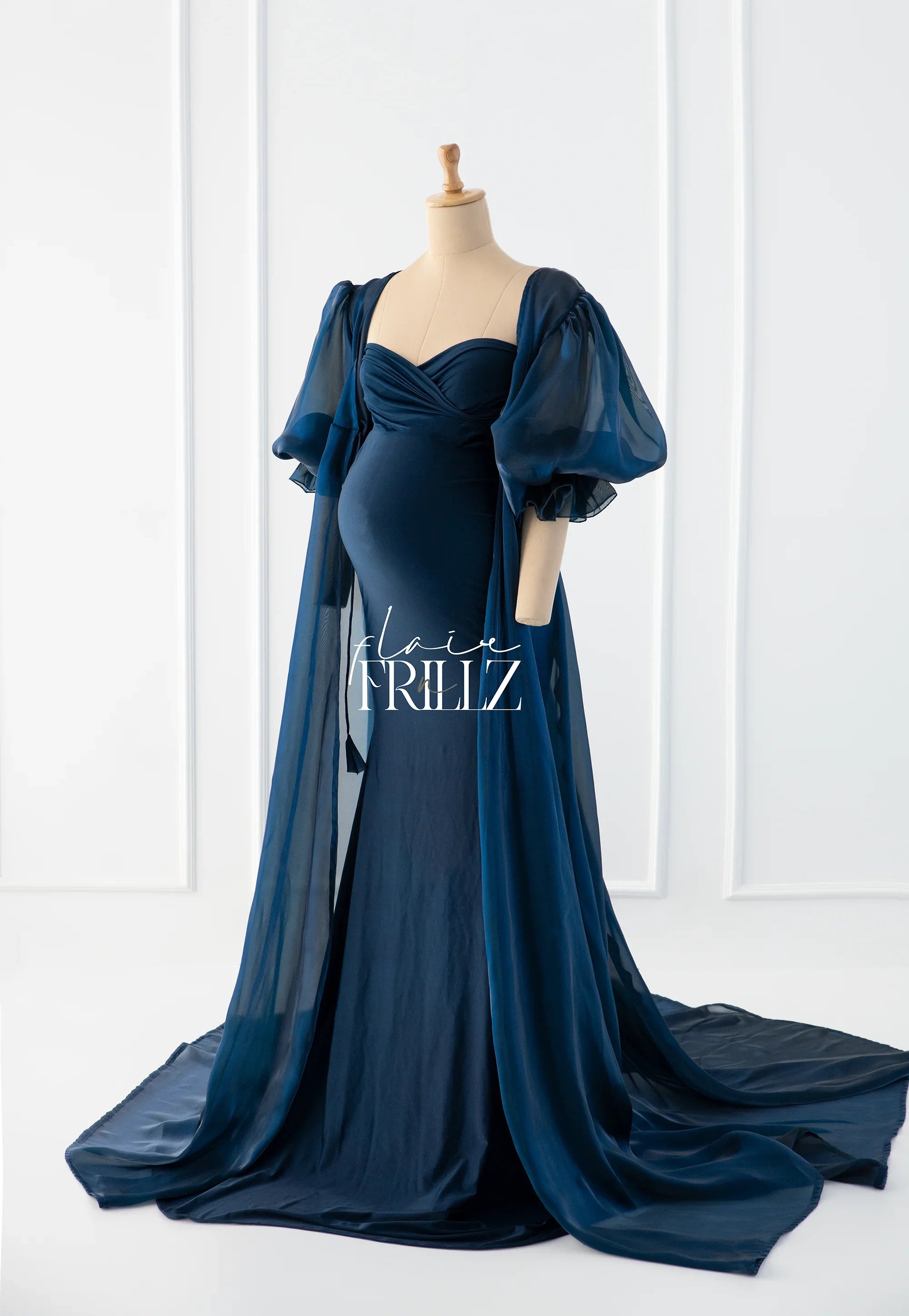 Navy blue maternity gown with puff sleeves and long sheer train on mannequin