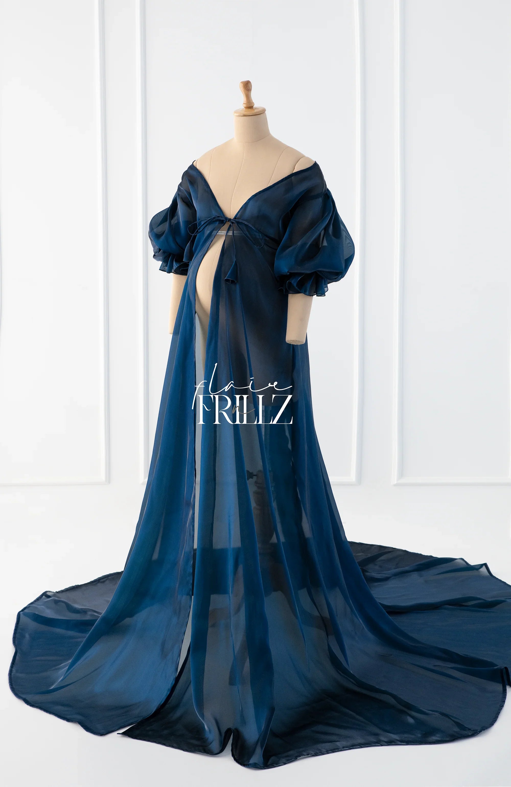 Sheer navy blue maternity gown with puff sleeves and floor-length train on mannequin