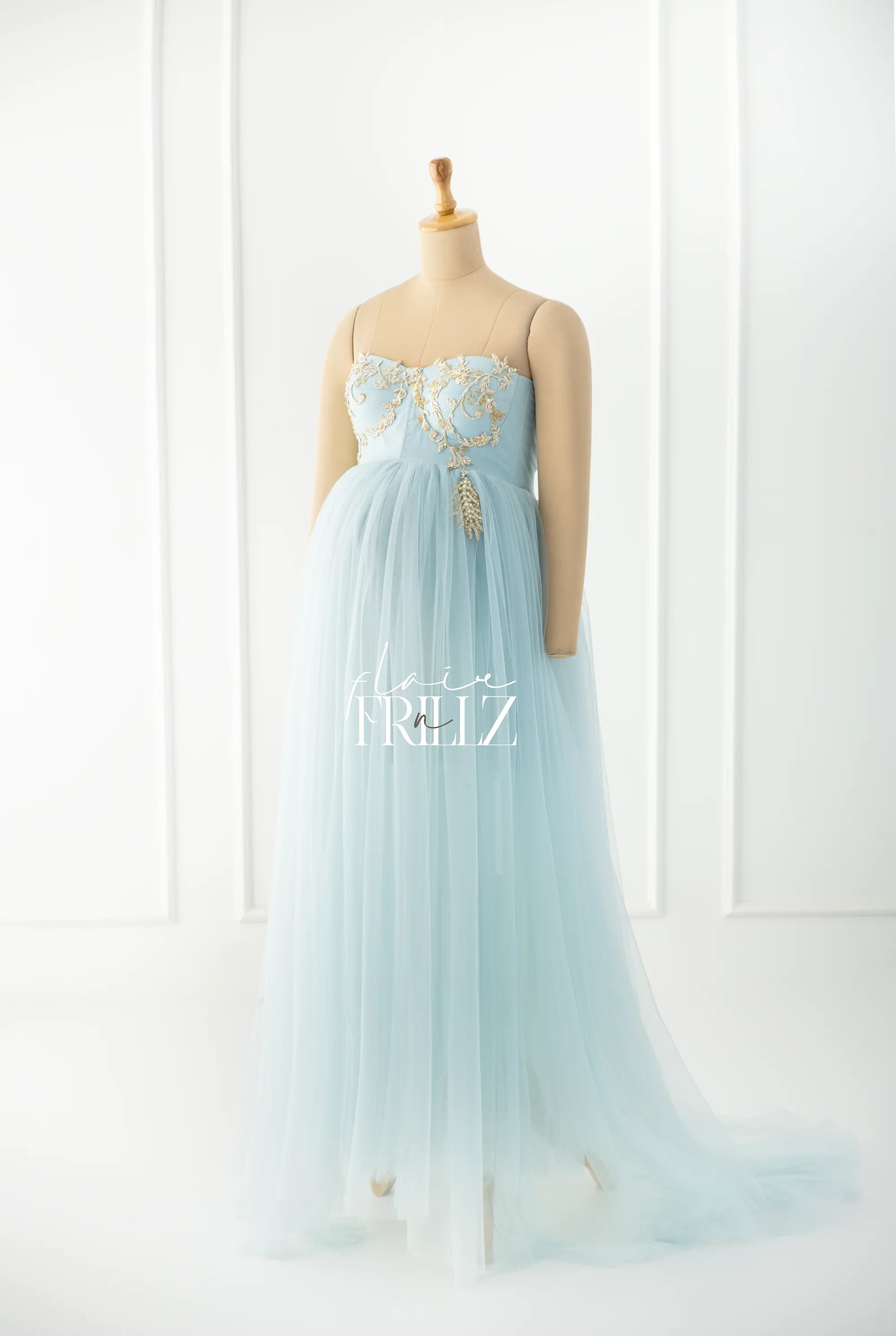 Light blue maternity gown with tulle skirt and gold embroidery on bodice, displayed on mannequin