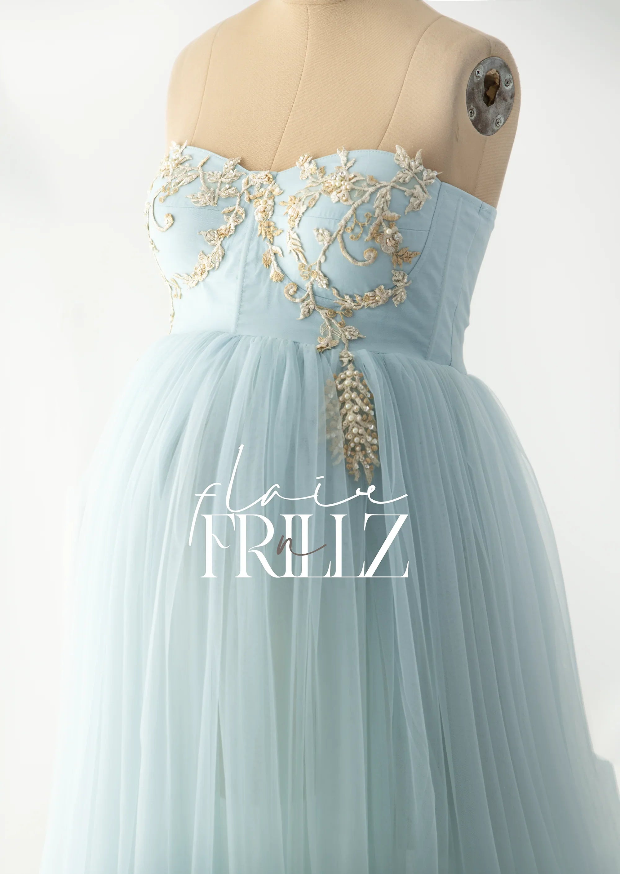Light blue strapless maternity gown with gold floral embroidery on a dress form