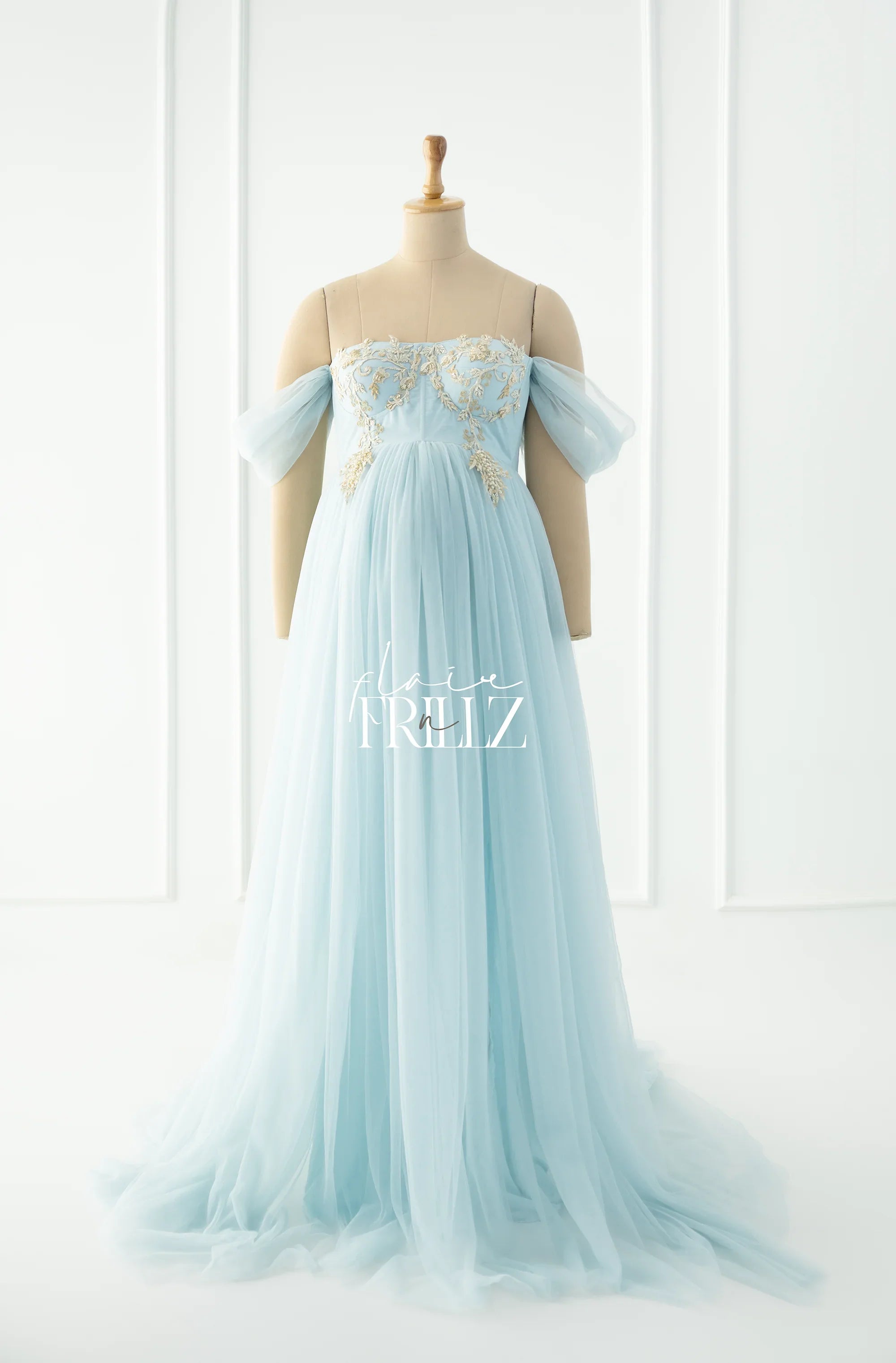 Light blue off-shoulder maternity gown with gold embroidery, displayed on a mannequin