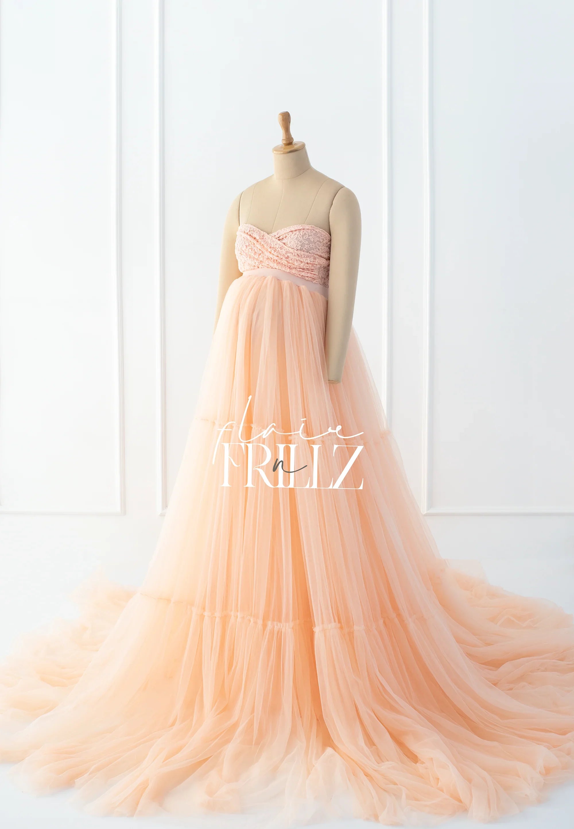 Peach strapless maternity gown with lace bodice and flowing tulle skirt on mannequin