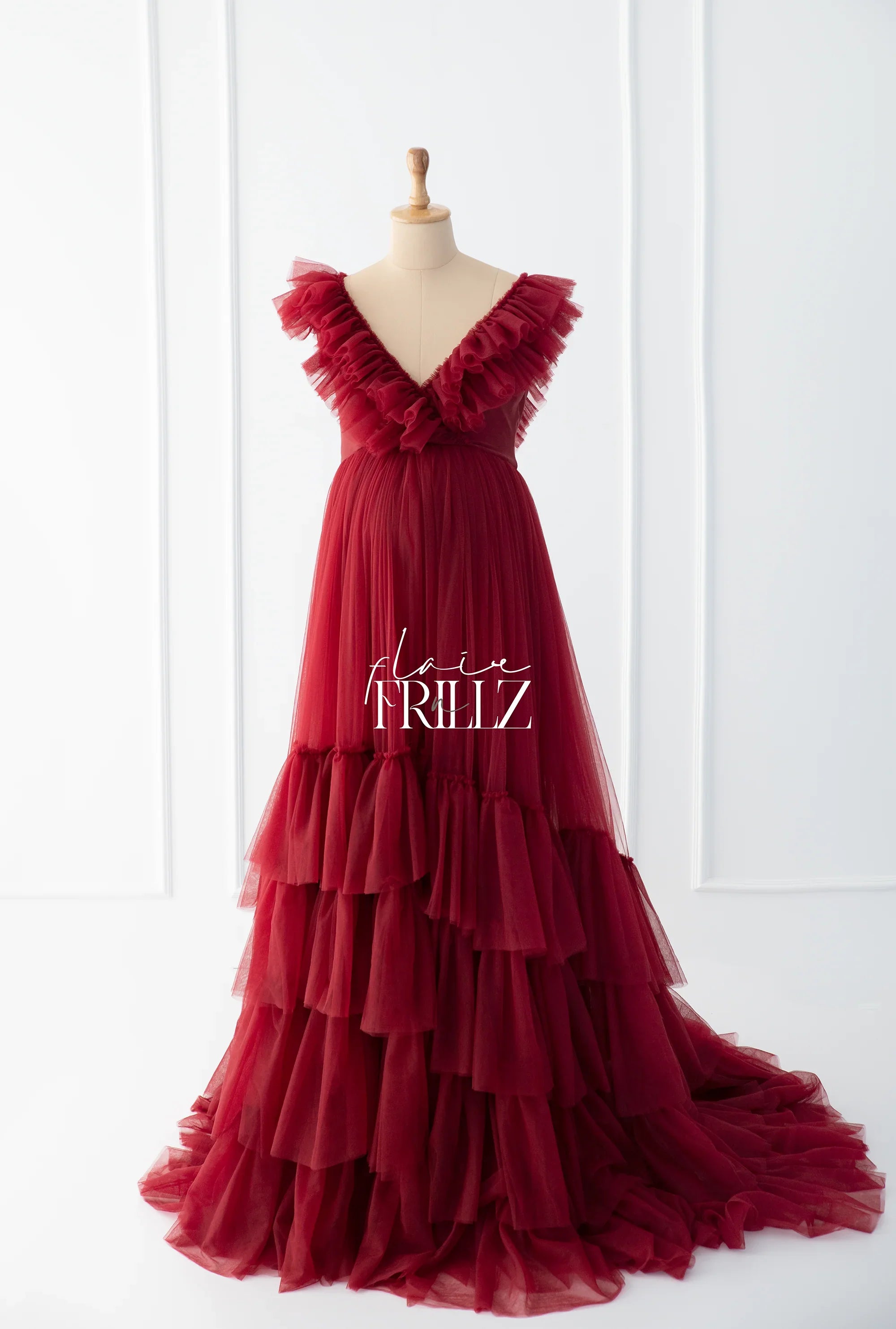Maroon ruffled maternity gown with tiered layers on a mannequin, elegant and flowing style