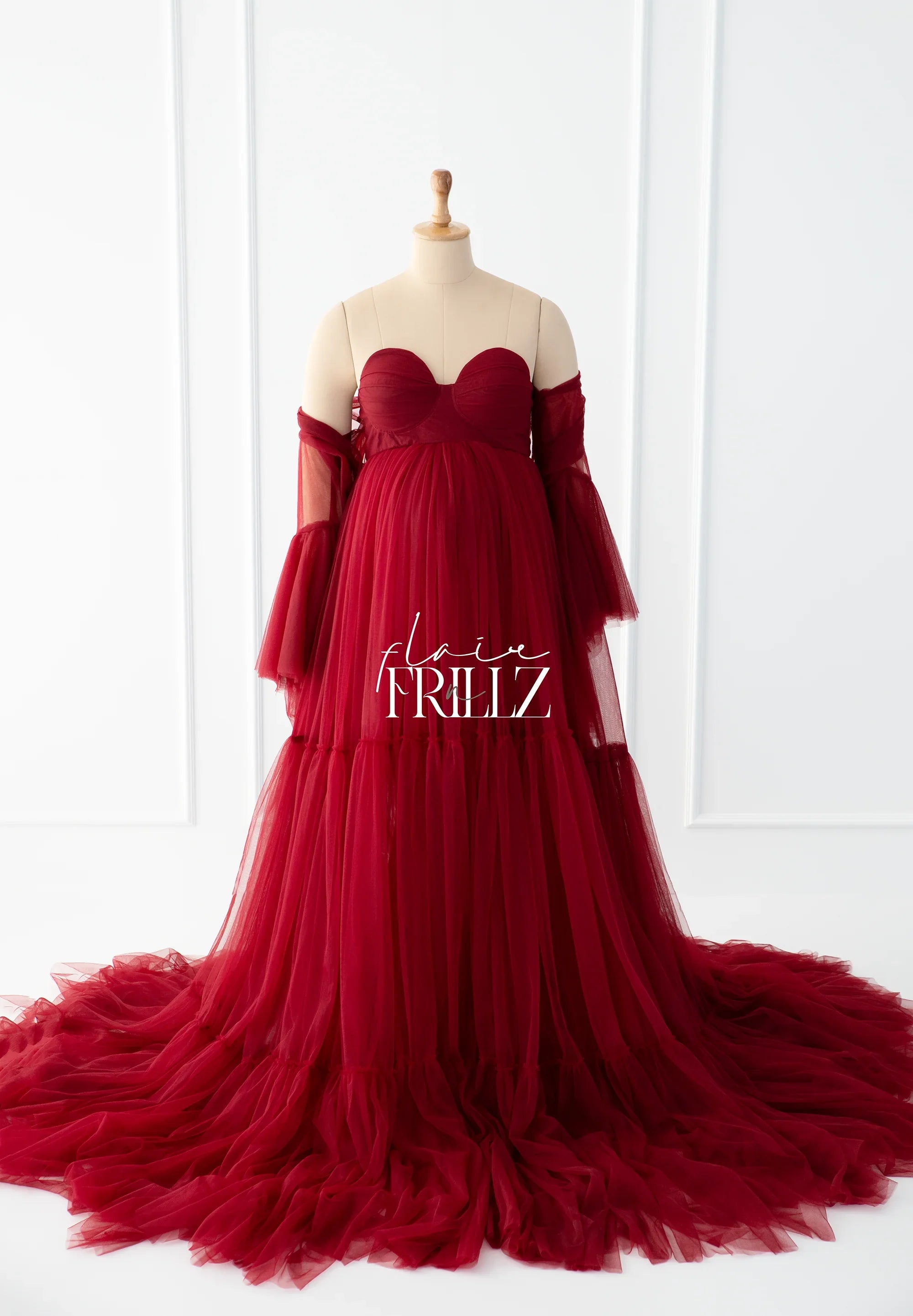 Elegant burgundy maternity gown with sweetheart neckline and flowing tulle skirt on mannequin