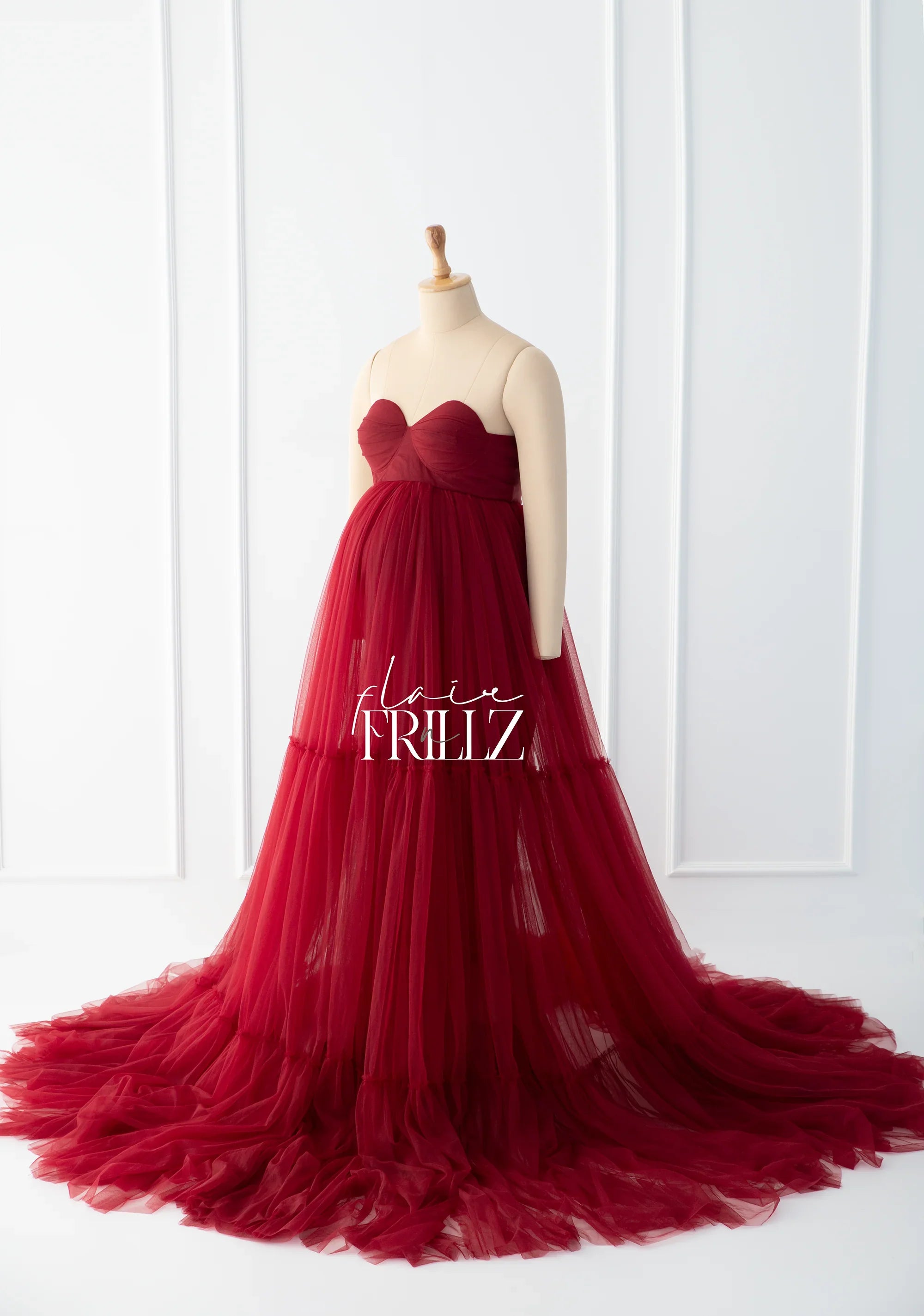 Elegant burgundy strapless maternity gown with tulle skirt displayed on mannequin