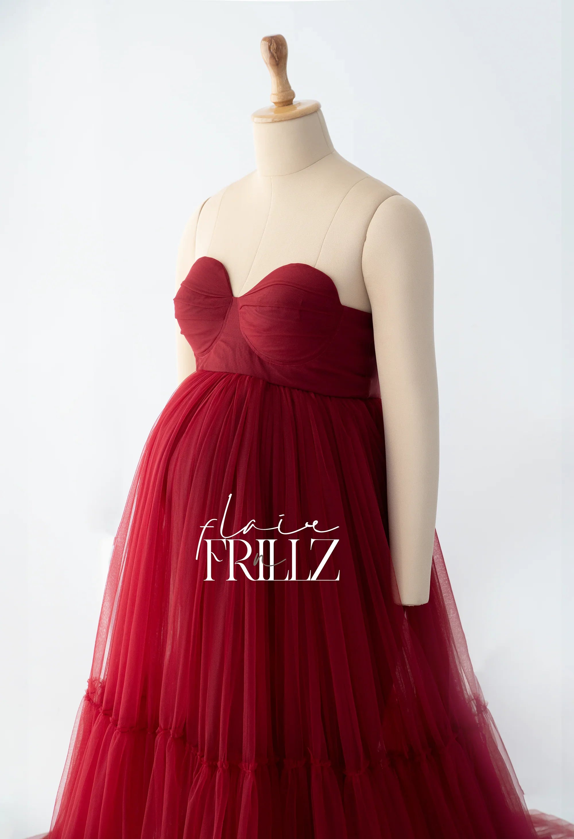 Burgundy strapless maternity gown with tulle skirt on mannequin, elegant pregnancy dress