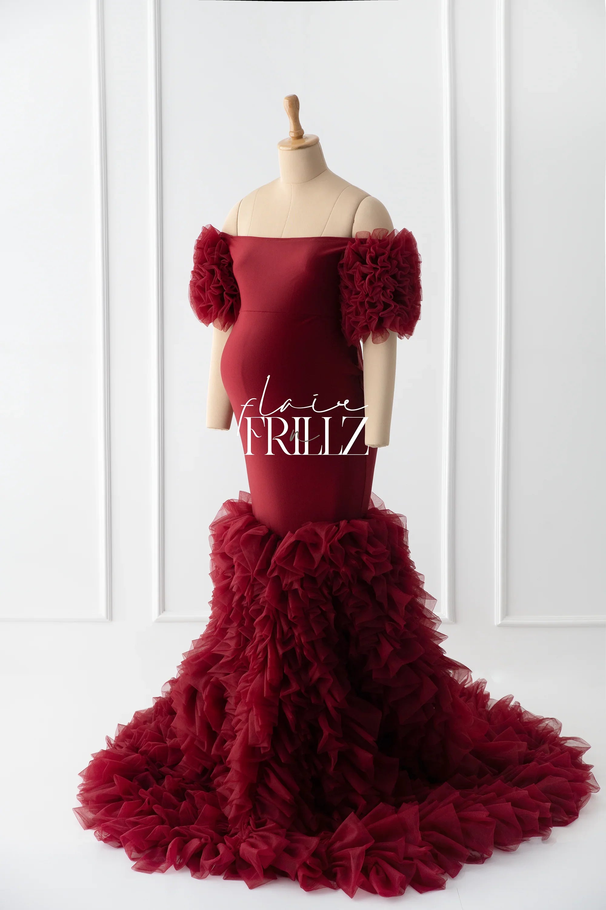 Burgundy maternity gown with ruffled sleeves and dramatic tulle train on mannequin