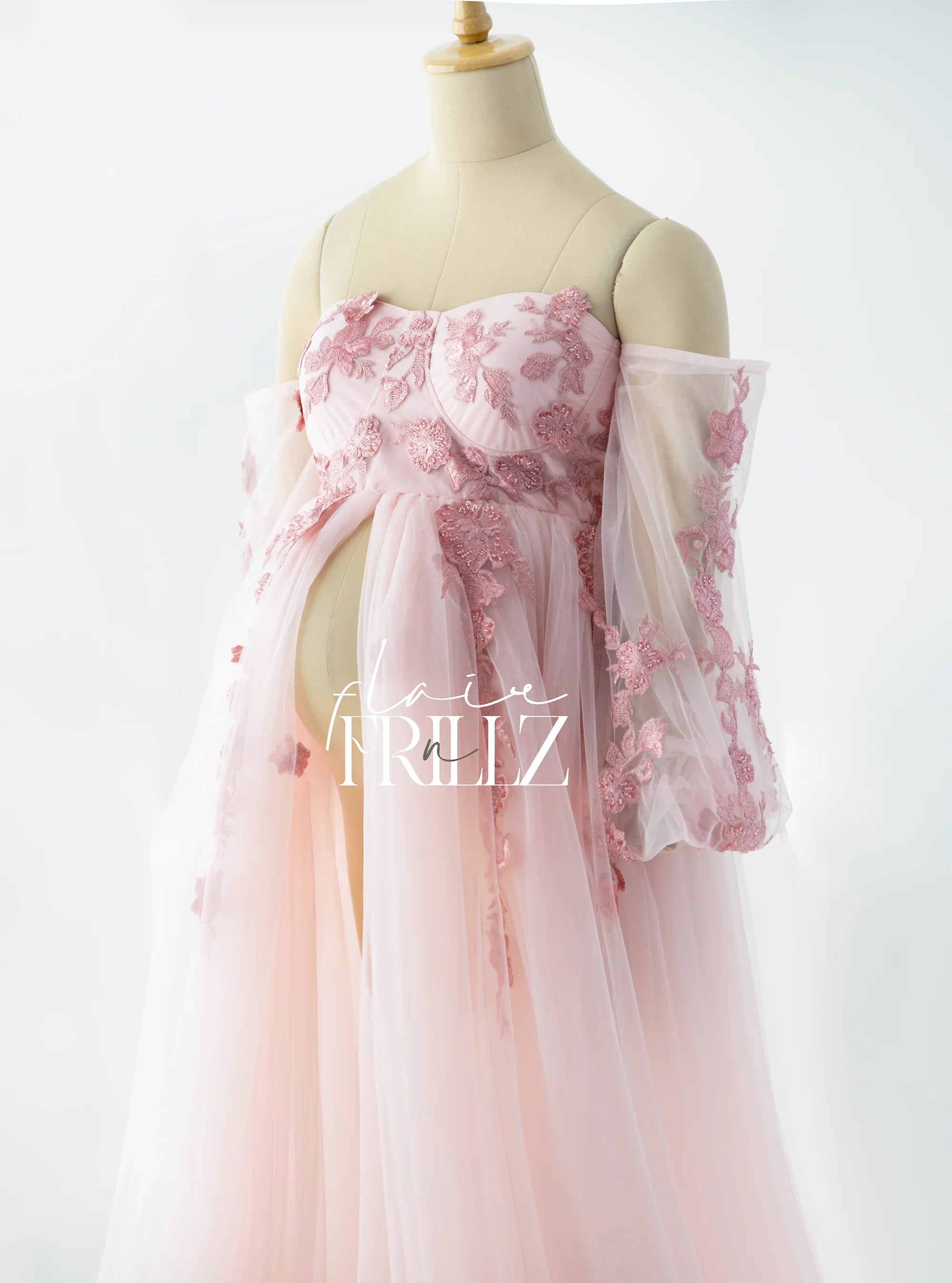 Pink floral maternity gown with sheer tulle sleeves on a mannequin