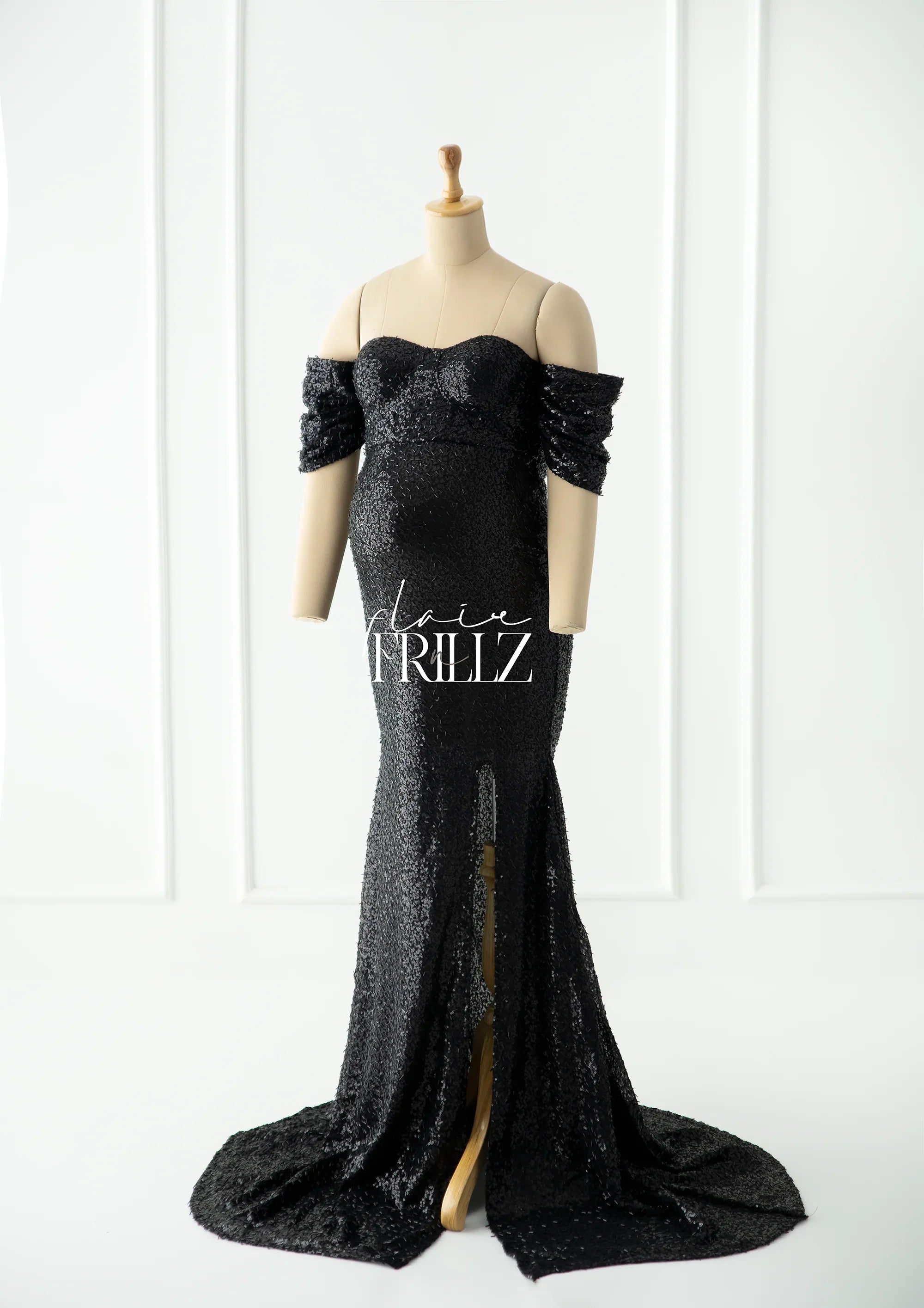 Black sequin maternity gown with off-shoulder sleeves and front slit on mannequin