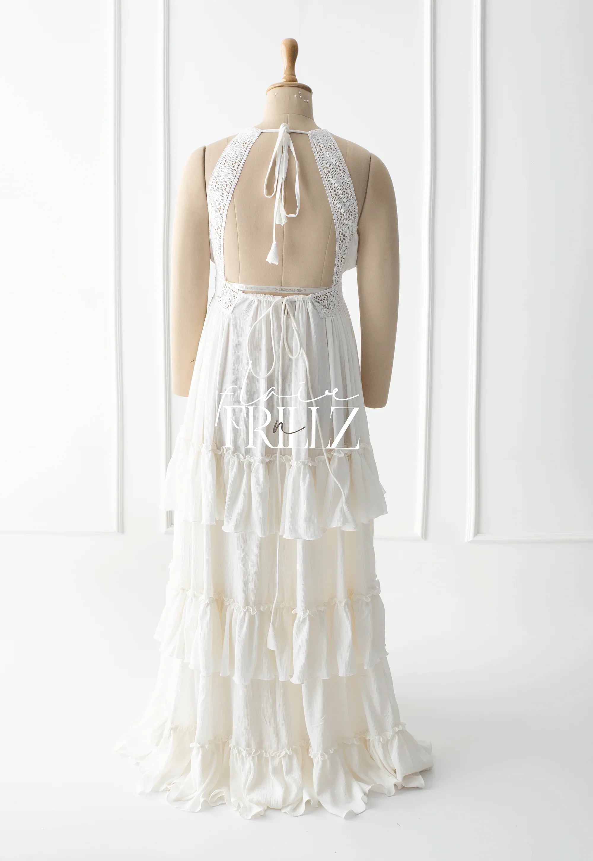 Elegant white maternity gown with lace straps and tiered ruffle skirt on mannequin