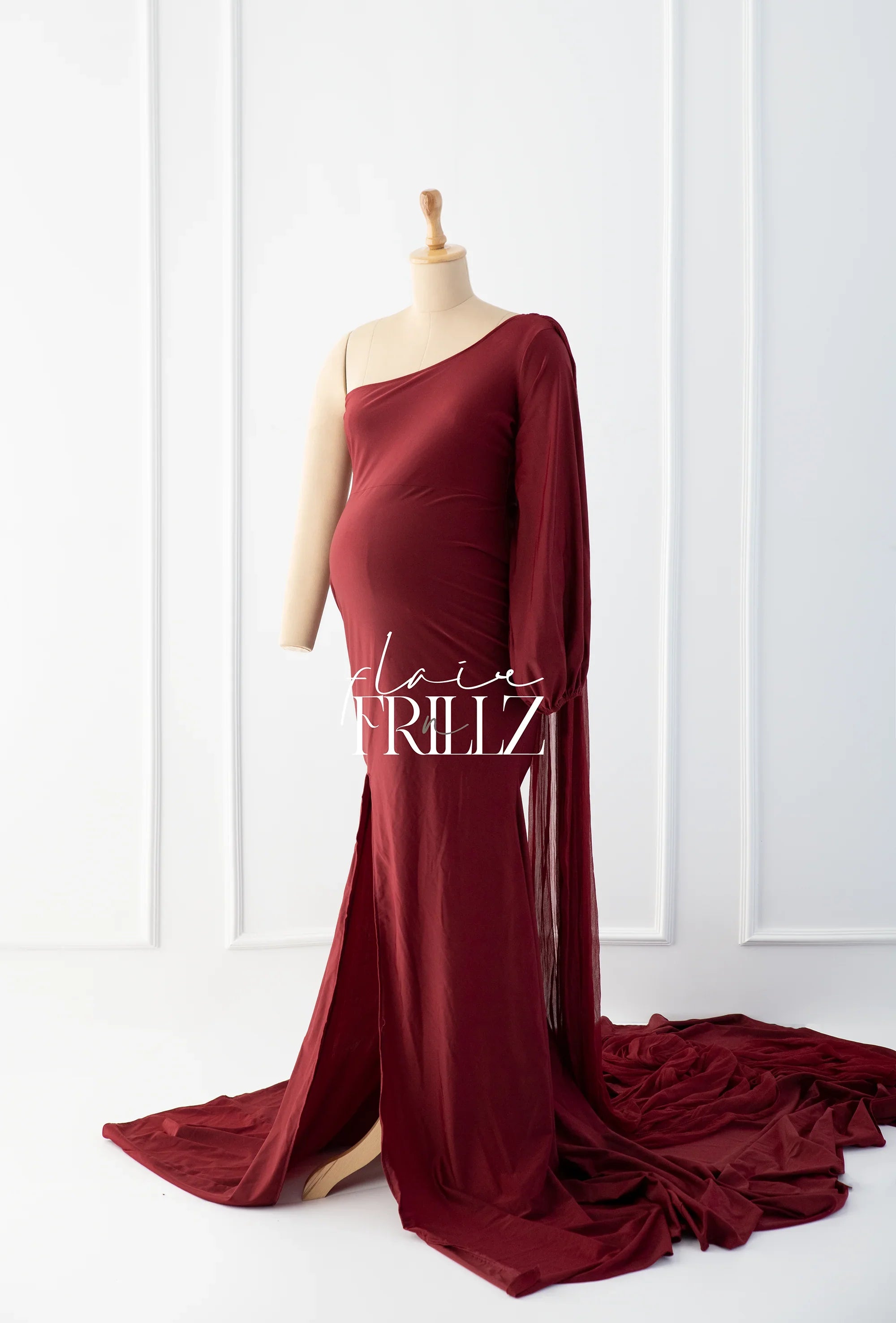 Burgundy one-shoulder maternity gown with long train on mannequin, elegant pregnancy dress
