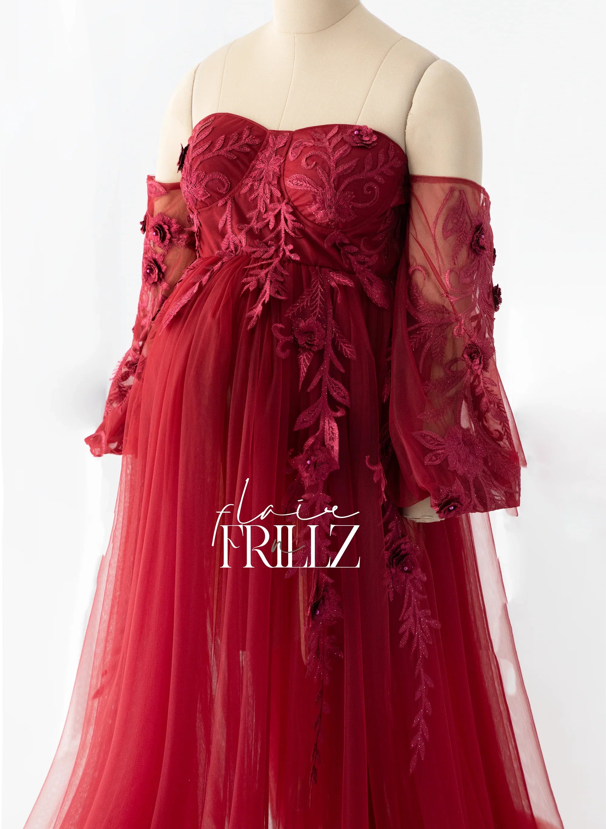 Red maternity gown with floral lace embroidery and sheer long sleeves on mannequin