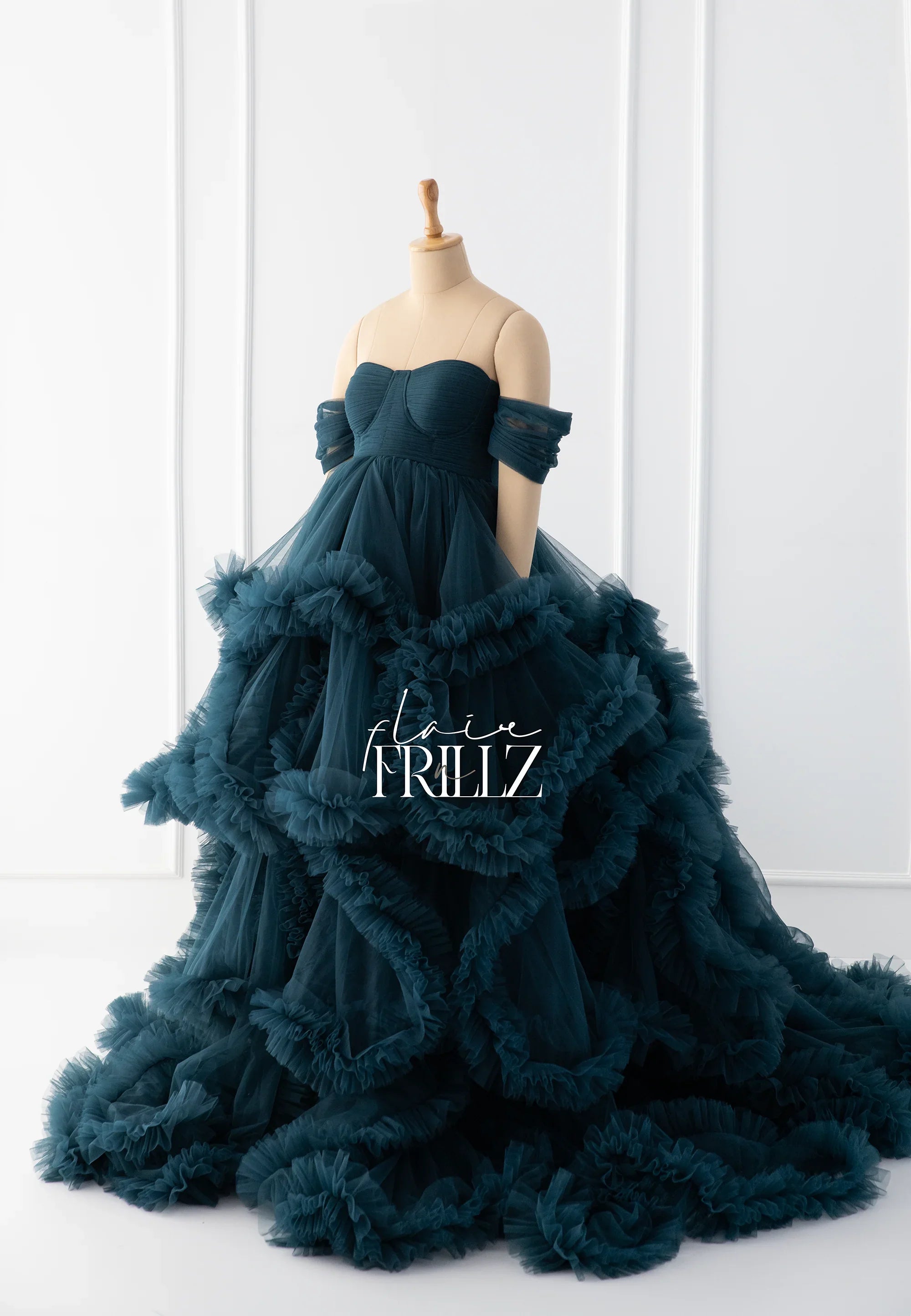 Dark teal maternity gown with ruffled tulle layers and off-shoulder sleeves on mannequin