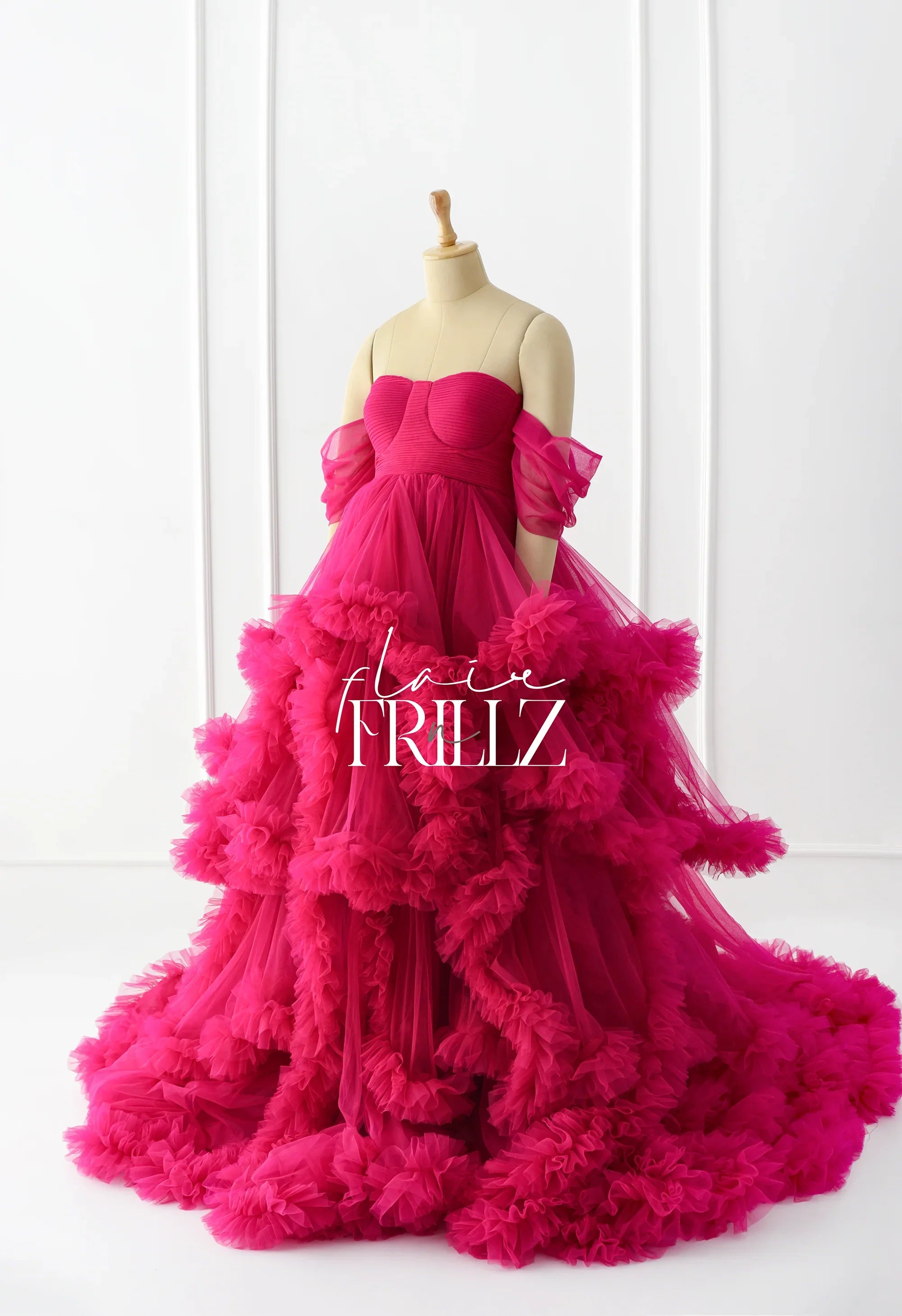Hot pink ruffled maternity gown with off-shoulder tulle sleeves on a mannequin