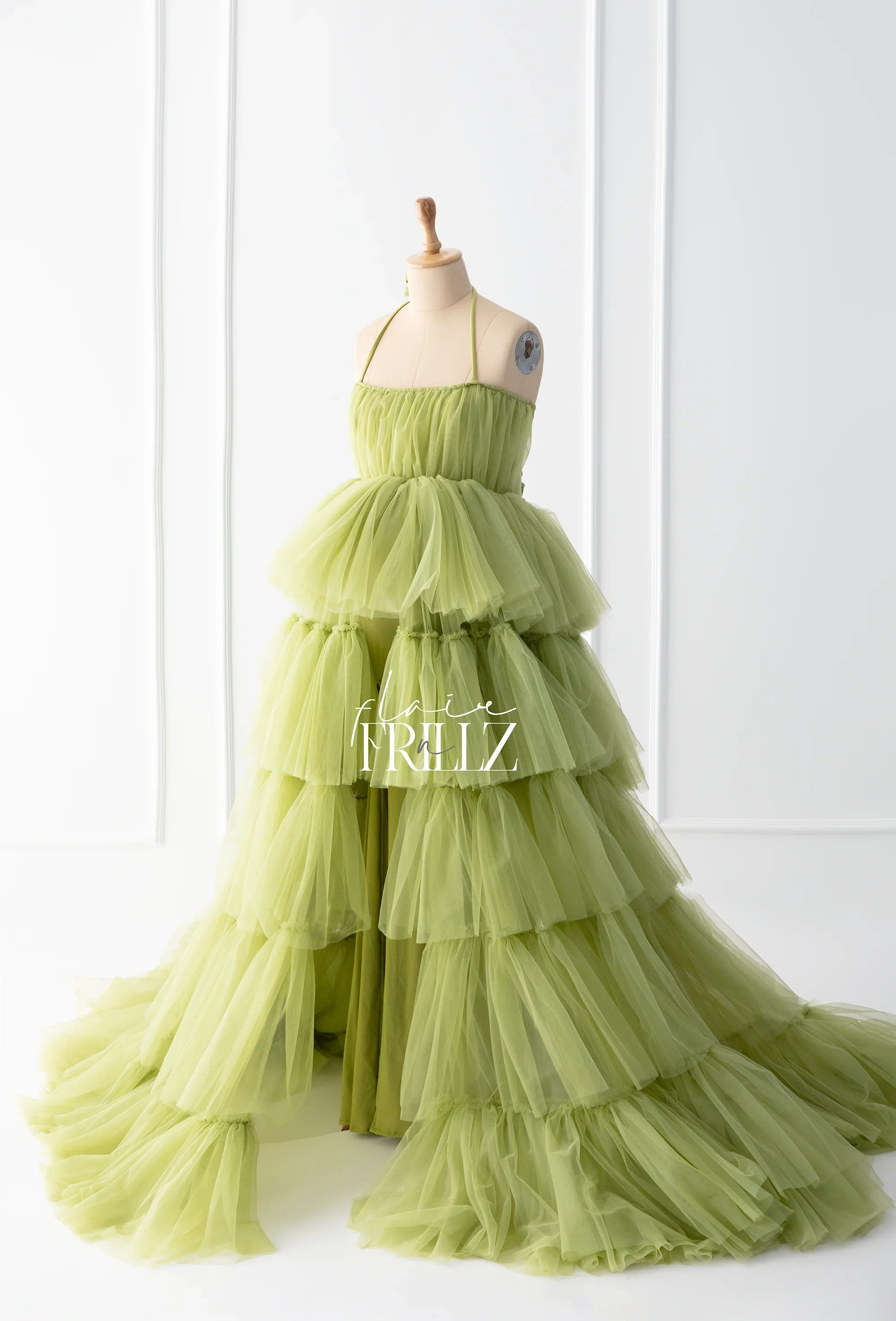 Tiered light green tulle maternity gown with halter neck on dress form in studio setting