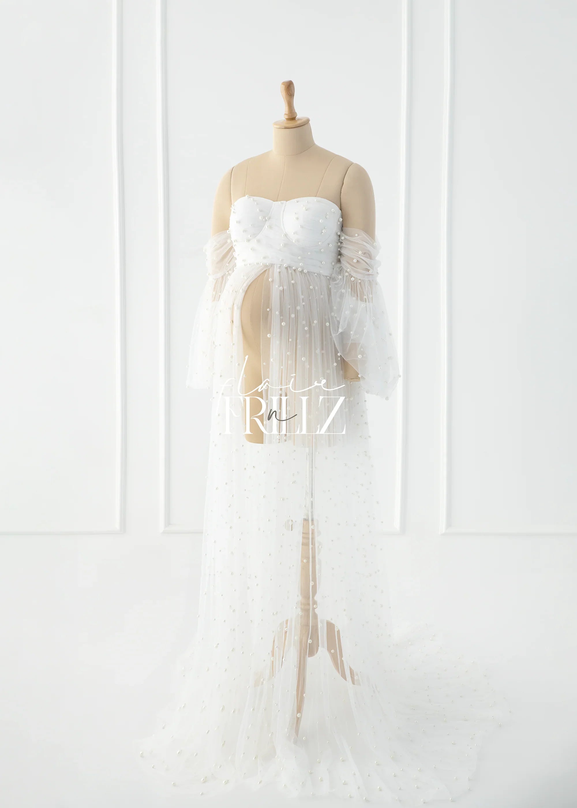 White pearl maternity gown with sheer off-shoulder sleeves on mannequin