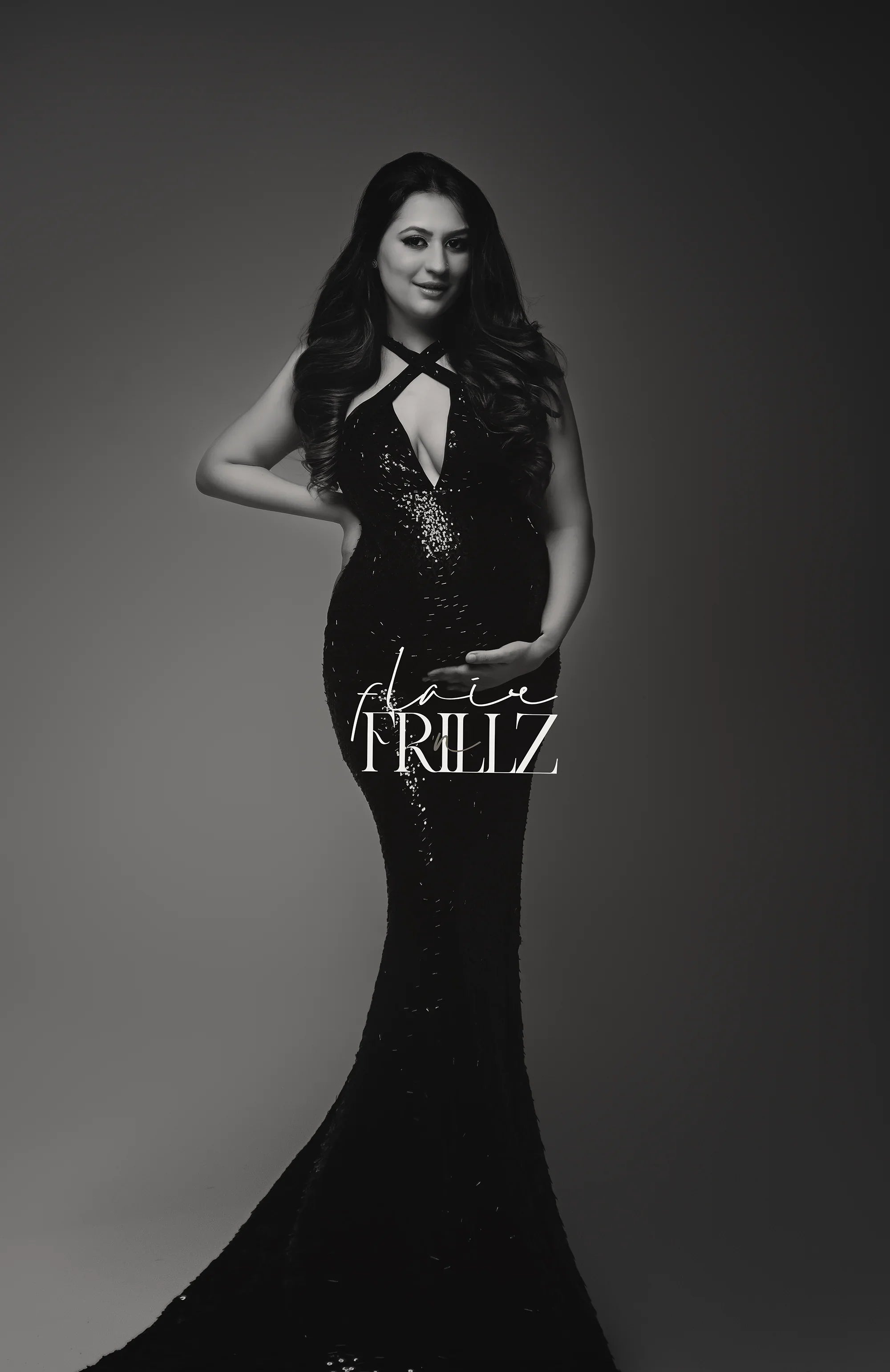 Pregnant woman in black sequin maternity gown with halter neckline, posing elegantly