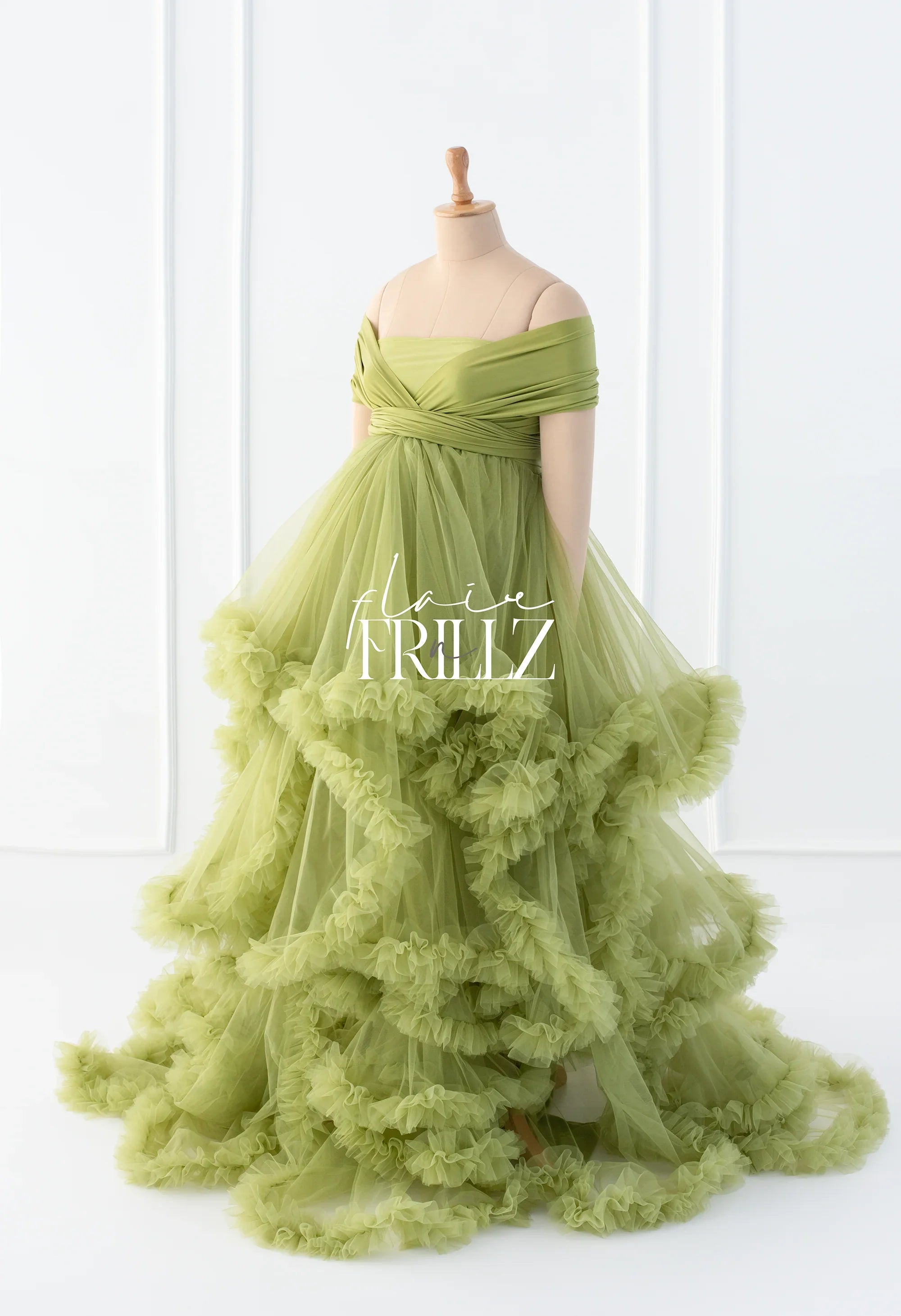 Green off-shoulder tulle maternity gown with ruffled layers on a mannequin