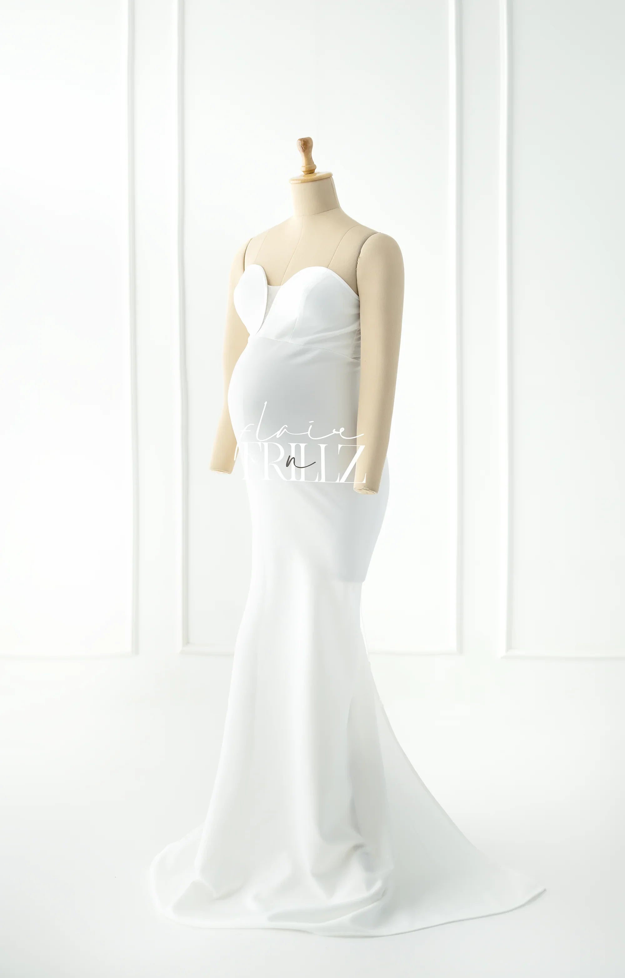 White strapless maternity gown with sweetheart neckline on mannequin in bright room