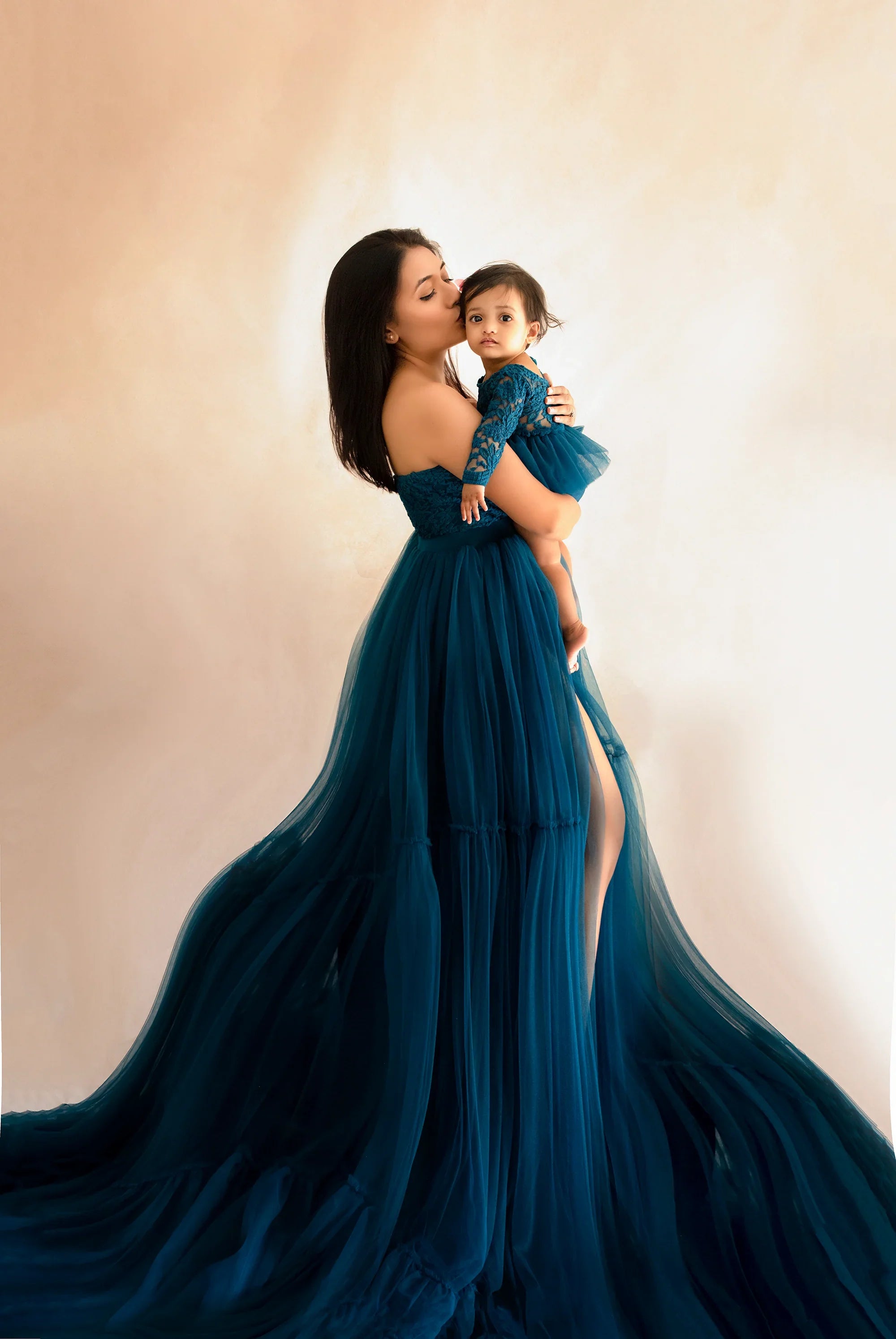Mother and child wearing matching teal tulle gowns, maternity fashion photoshoot