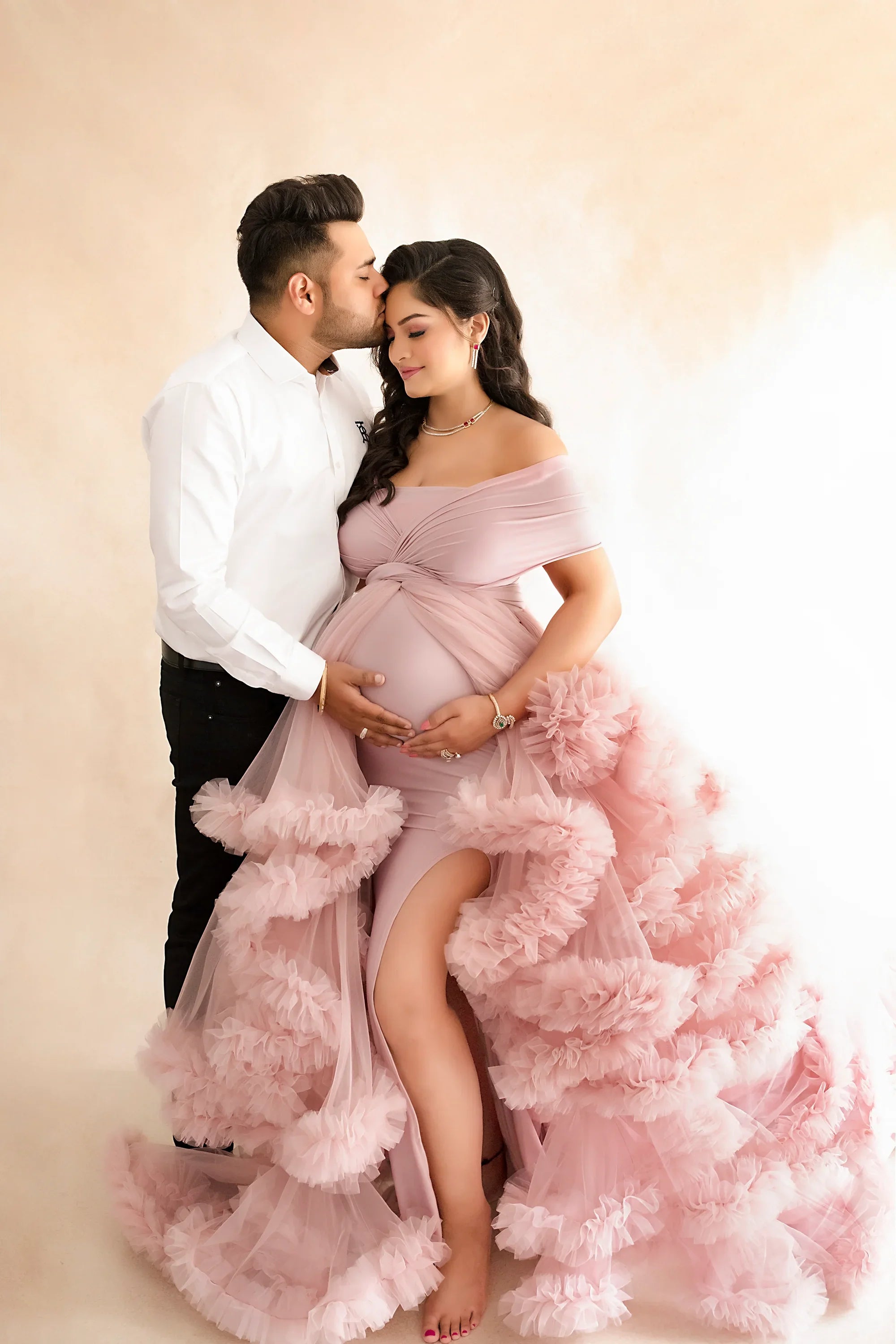 Elegant maternity shoot with woman in pink ruffled gown and partner in white shirt