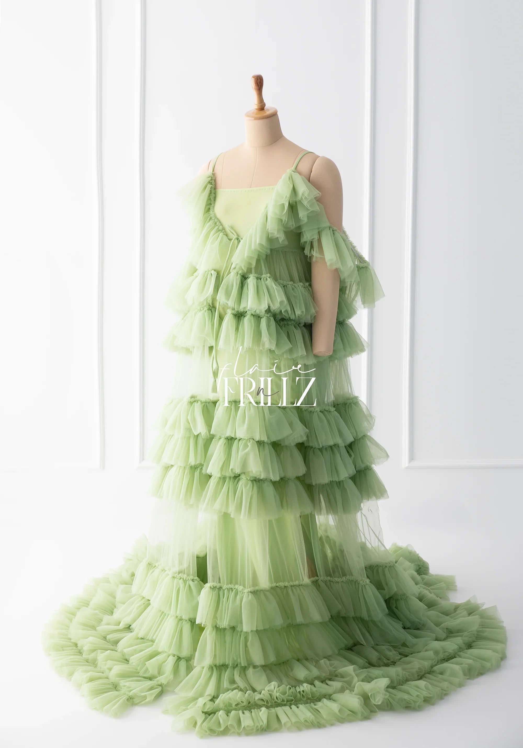 Light green ruffled maternity gown with layered tulle and train on a mannequin.
