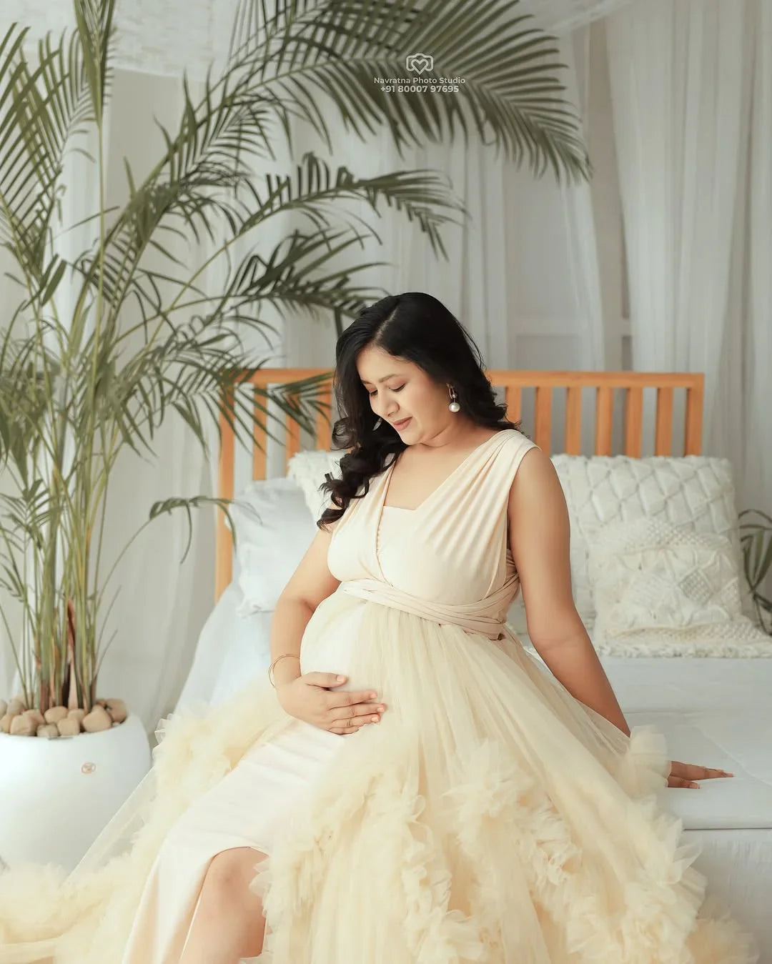 A model wearing the Aza Ivory Convertible Maternity Gown by FlairNFrillz, showcasing its elegant design and flowing fabric.
