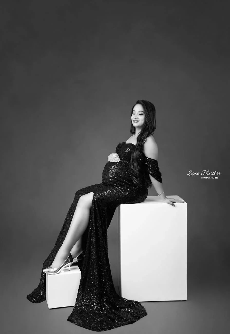 Pregnant woman in a stylish off-shoulder maternity gown posing in studio